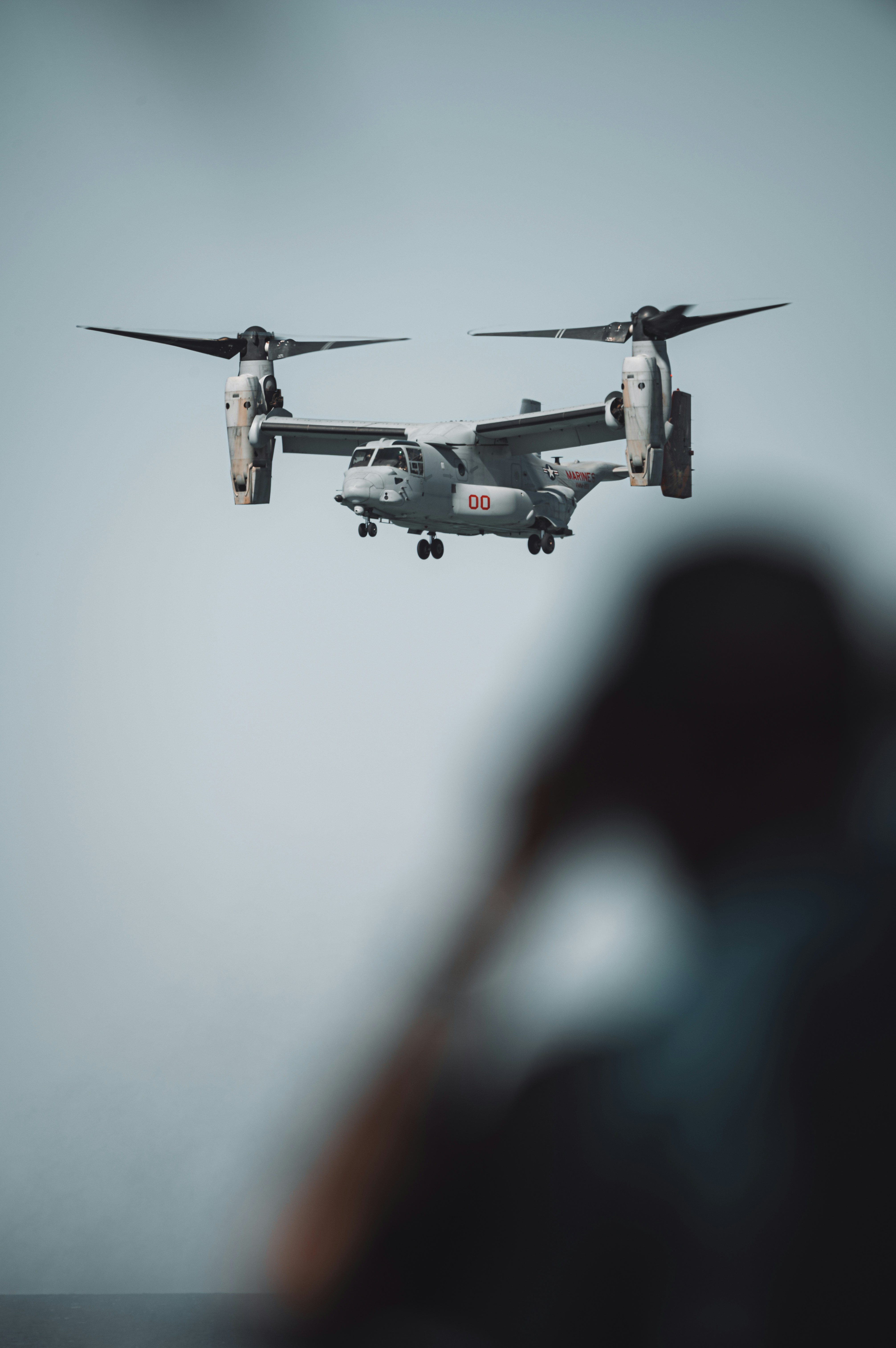 A person standing in front of an airplane flying in the sky