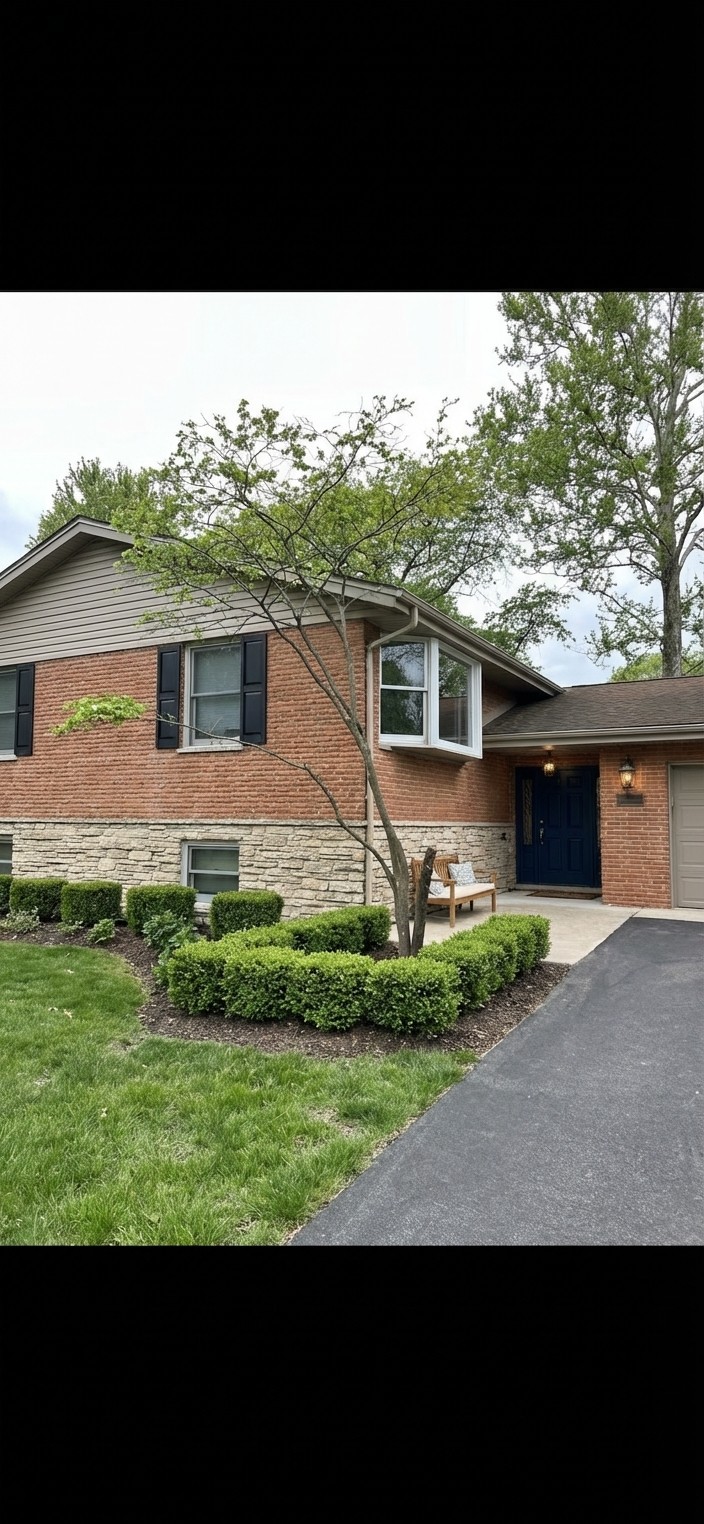 Classic revival. Taupe siding, navy door, functional black shutters, brass fixtures, boxwood hedges.