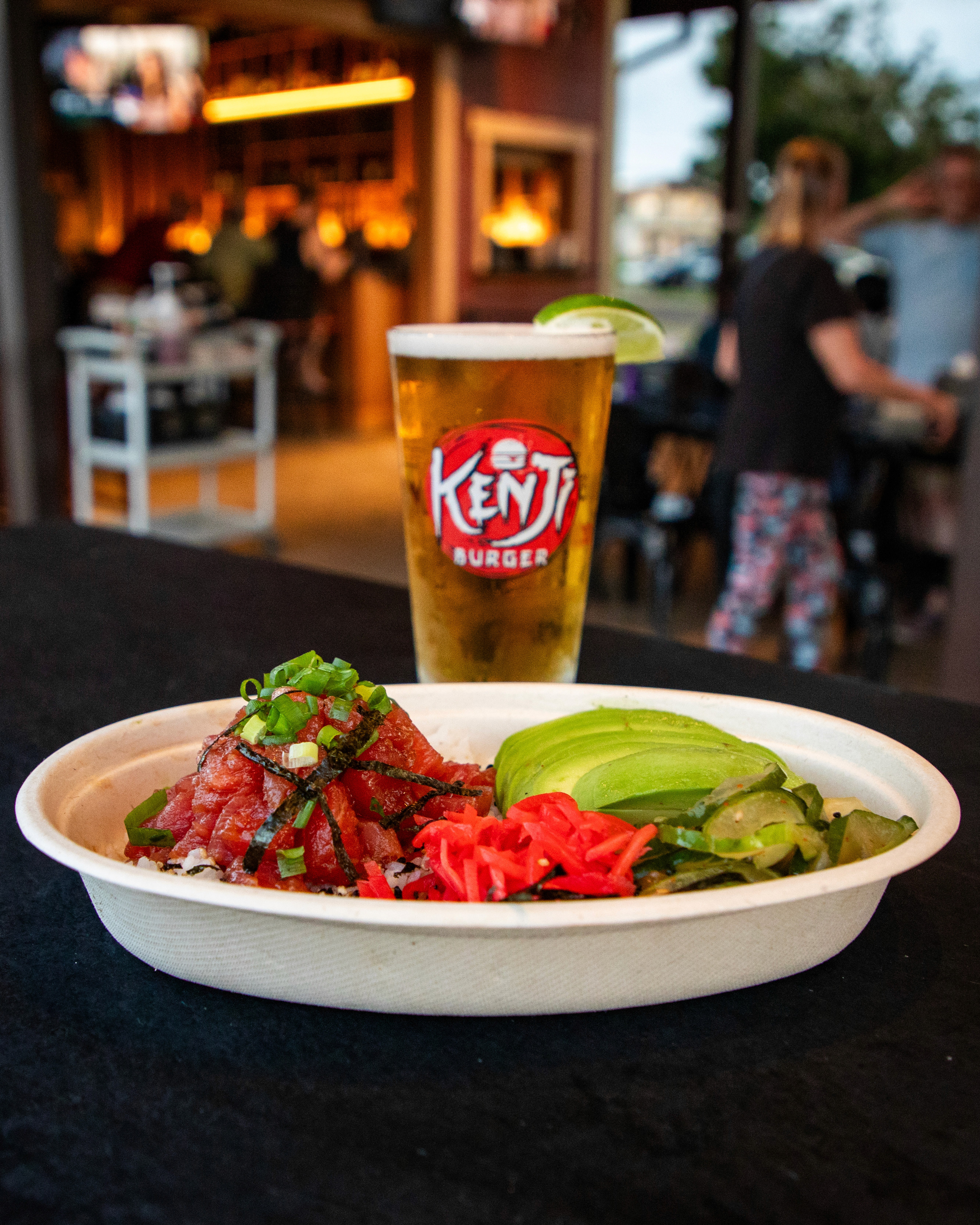 A large, perfectly seared fillet of salmon with crispy skin and a herb glaze, garnished with microgreens, fresh dill, and lemon wedges, presented on a dark wooden board against a black background.
