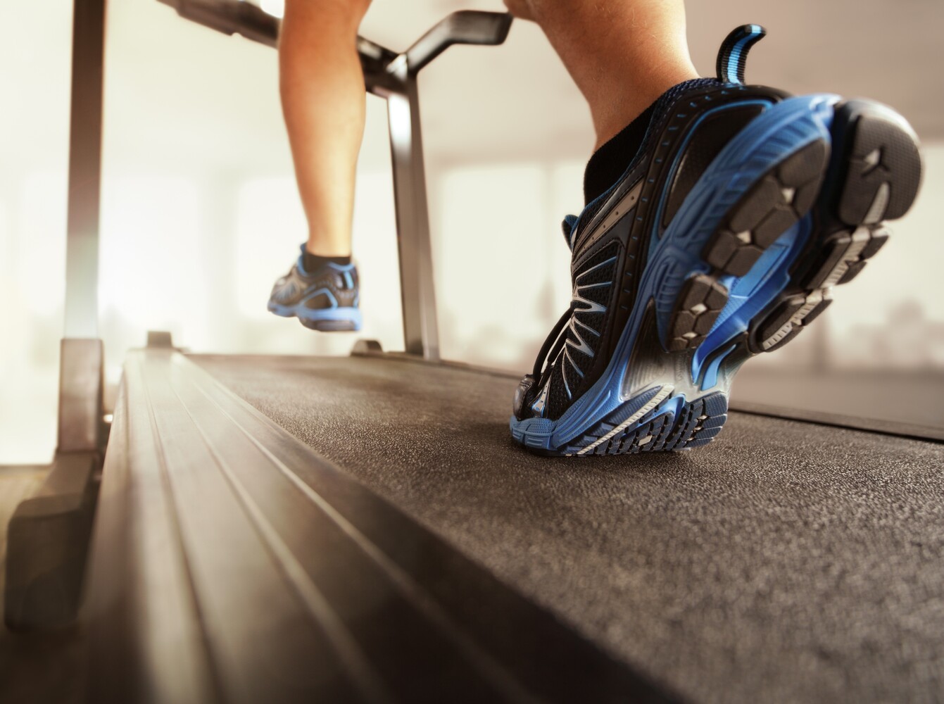feet of a man at the gym running on a treadmill for weight loss purposes