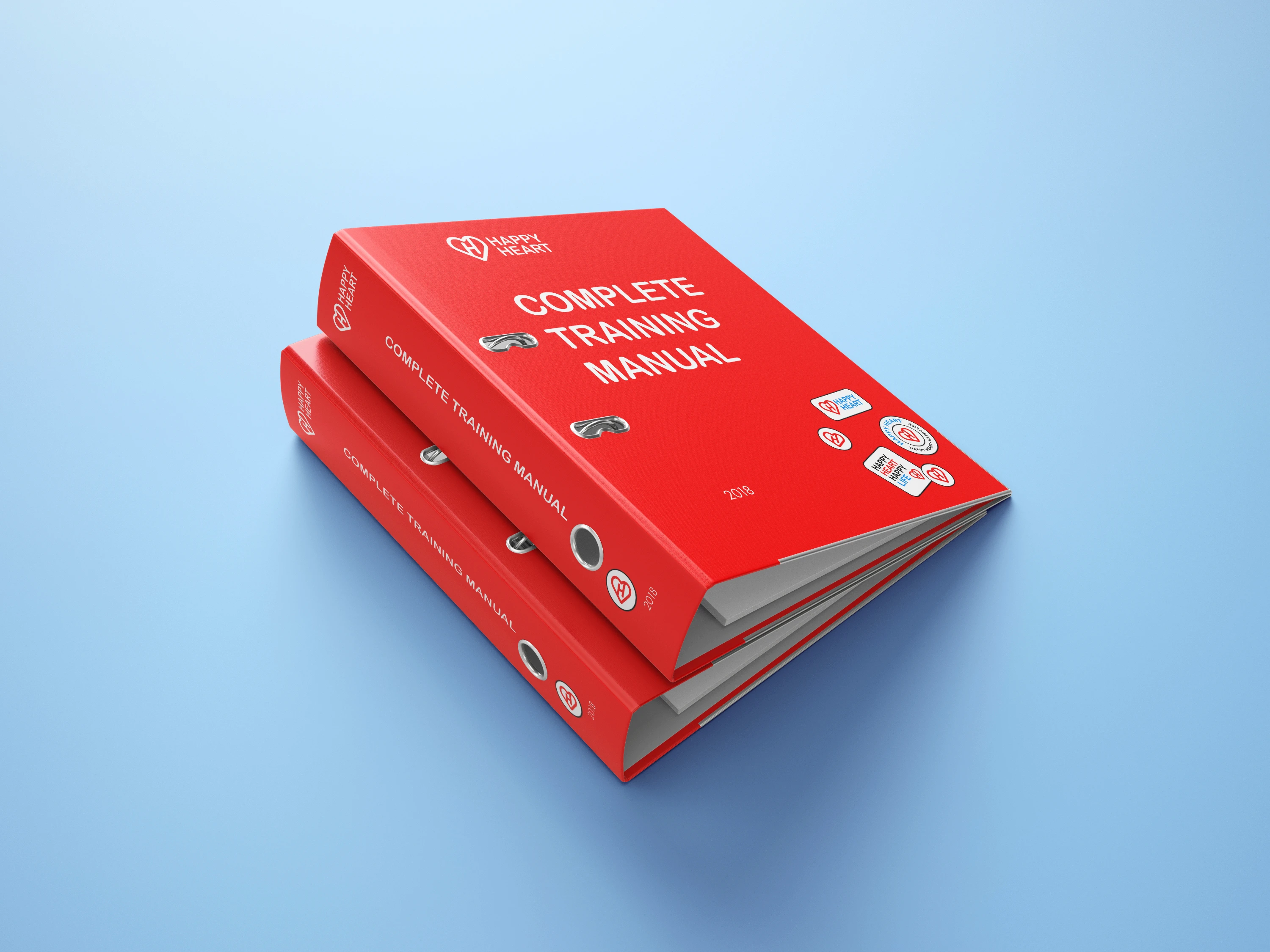 A red training manual book featuring the words "Training Manual" written on the cover sitting on soft blue surface.