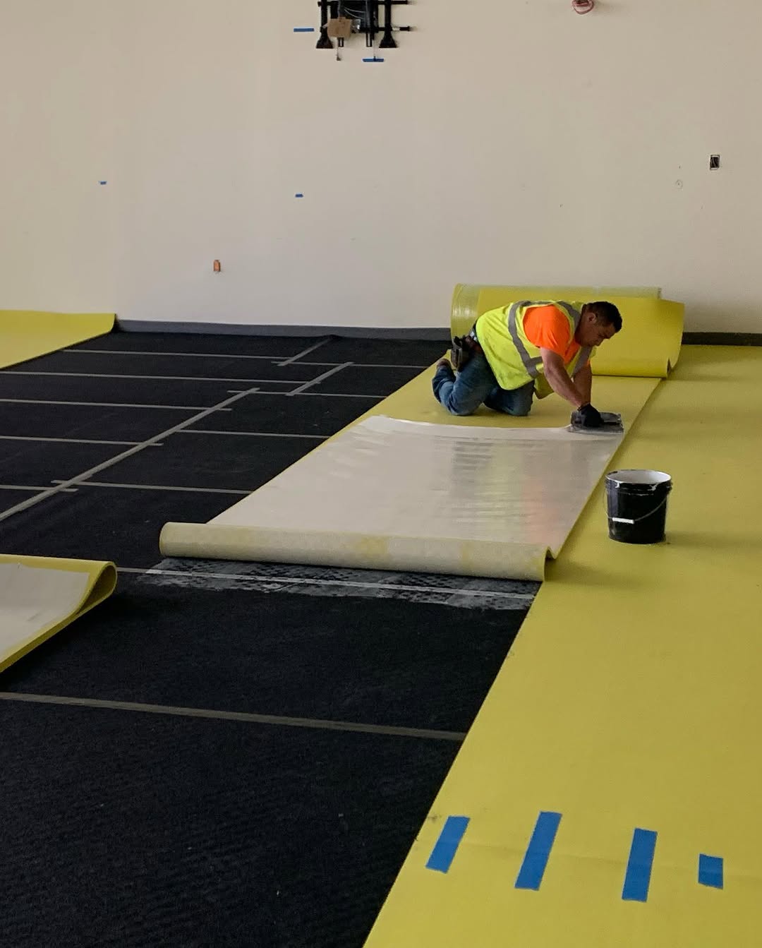 Yellow acoustic isolation mat rolled out over plywood underlayment