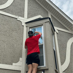 Window Wolf team member professionally cleaning second-story residential window on a Kansas City home