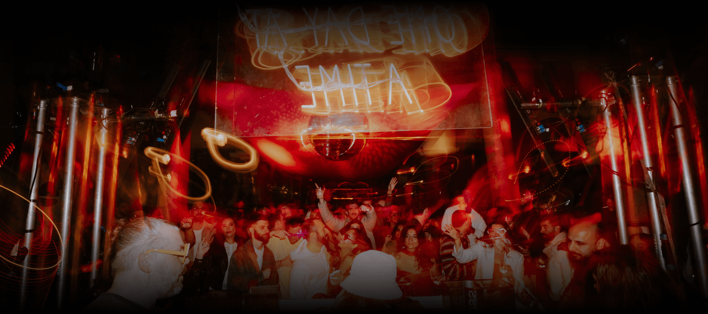 Smiling crowd dancing closely at ODAAT event, colorful lights creating lively club atmosphere.