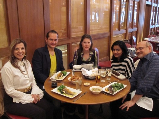 A photo of a group of people having lunch at a round restaurant table.
