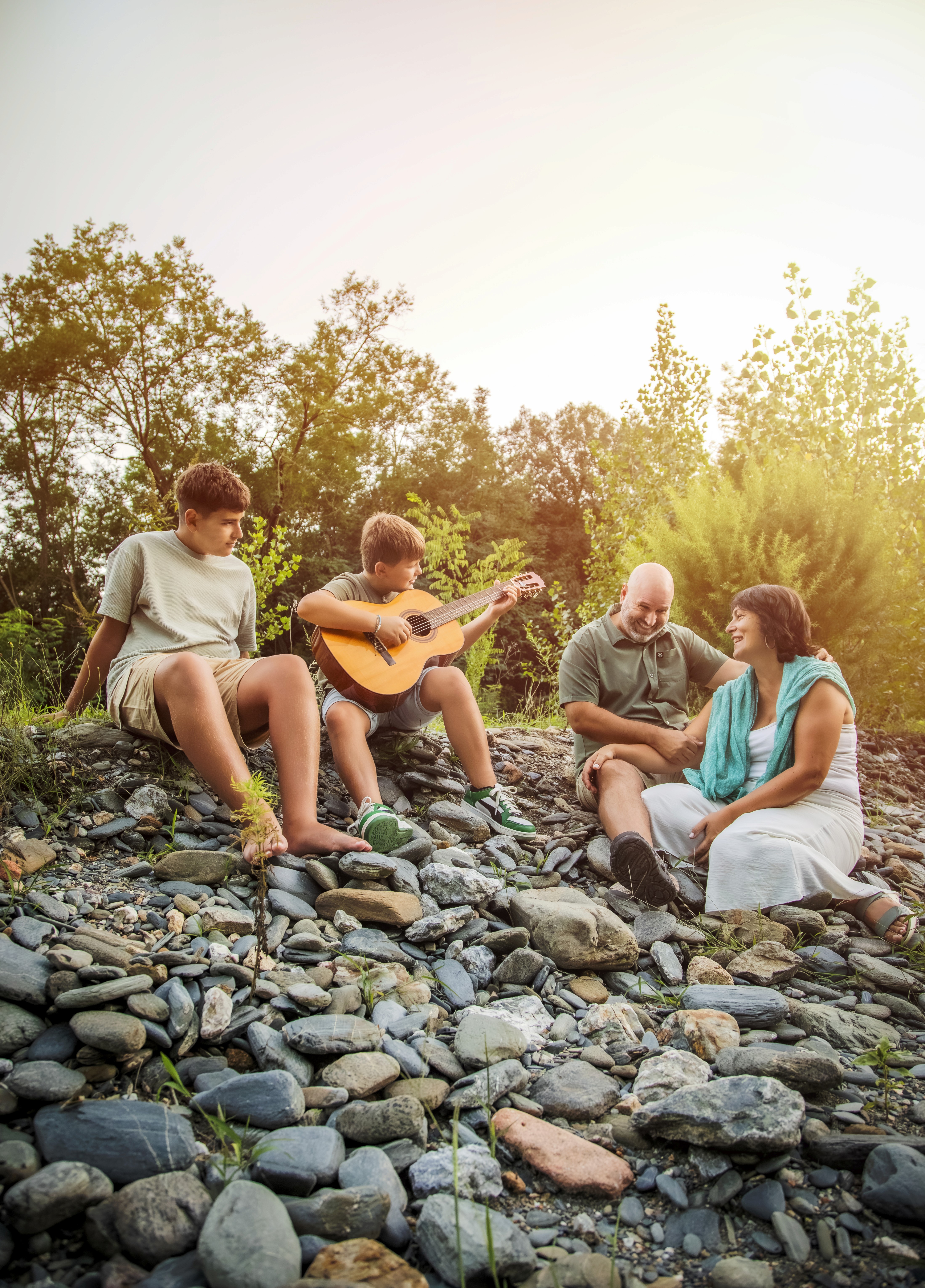 Familia sentados mientras uno de los hijos toca la guitarra