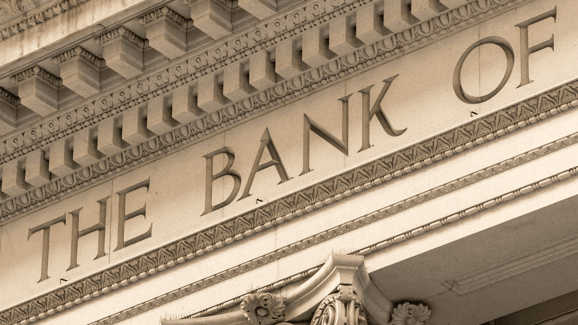 Bankwesen: Eine Nahaufnahme der steinernen Fassade eines klassischen Bankgebäudes mit der eingravierten Aufschrift „THE BANK OF“.