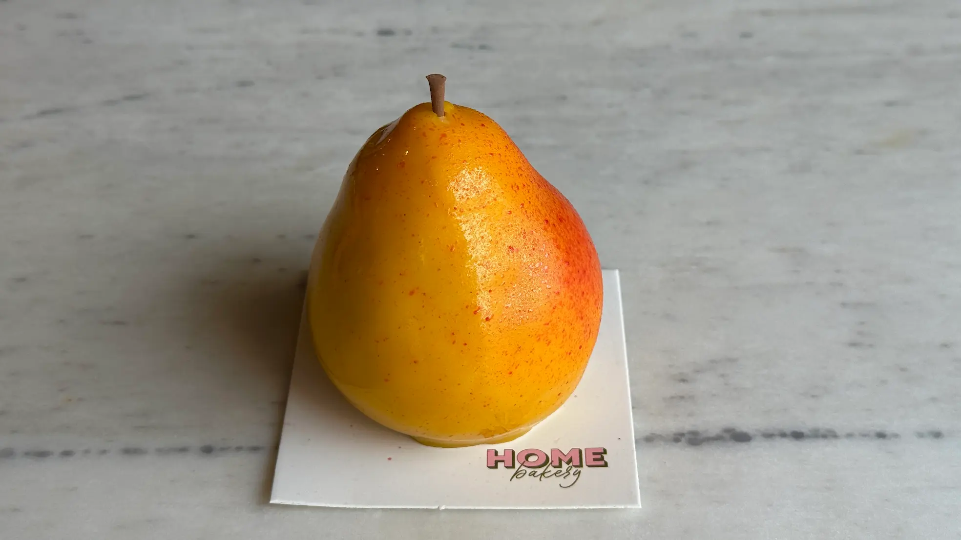 Pear-shaped mousse cake with gradient yellow-orange coloring and realistic stem
