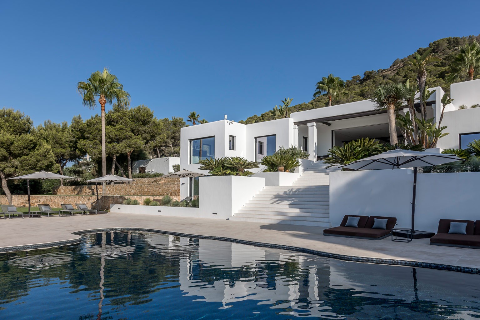 Exclusive luxury villa in Ibiza — front-right pool area view showing estate facade and sun loungers; private VIP estate property for weddings, events and holiday retreats with privacy.
