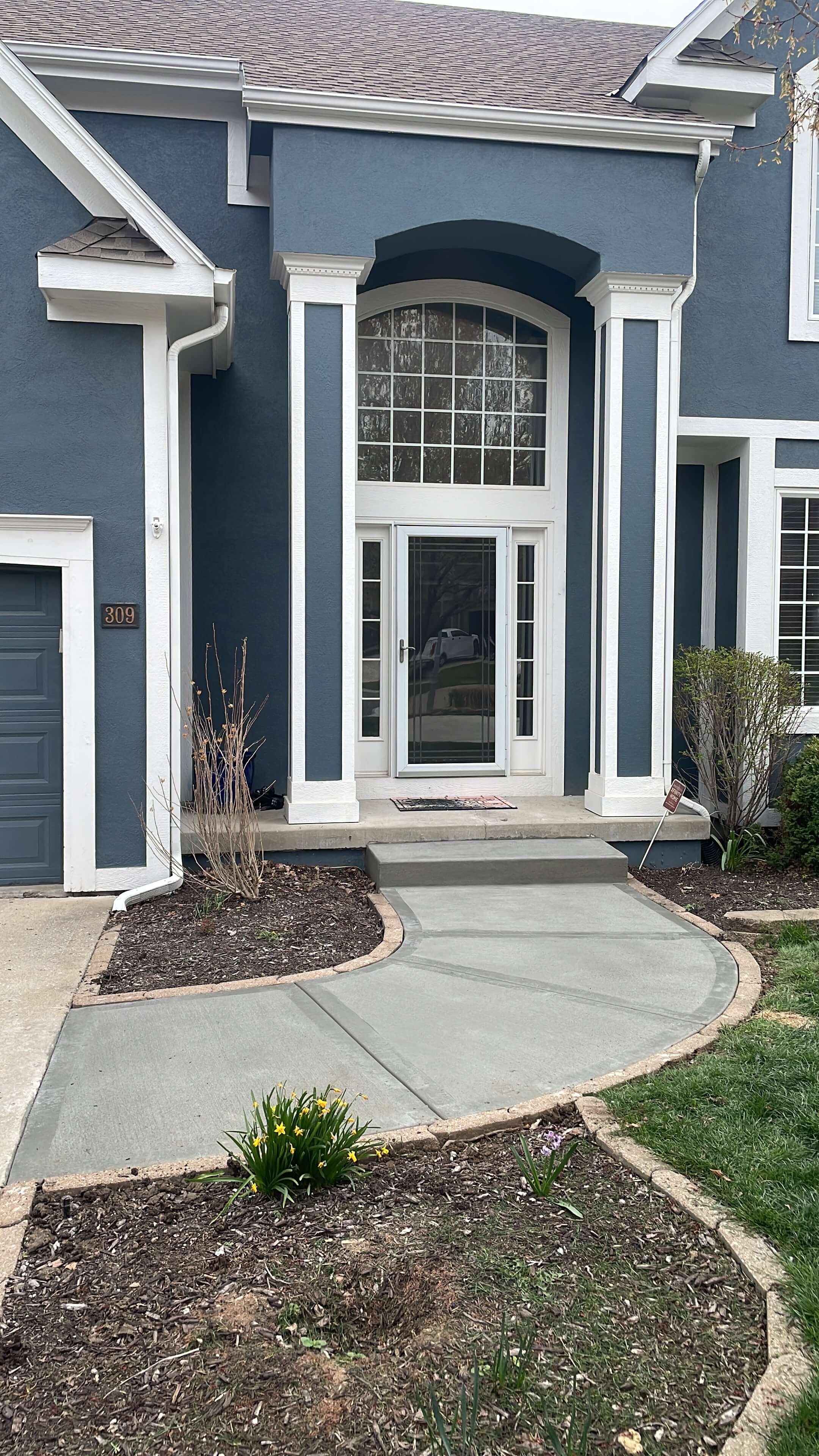An image showing a newly poured brushed sidewalk in front of a blue house.