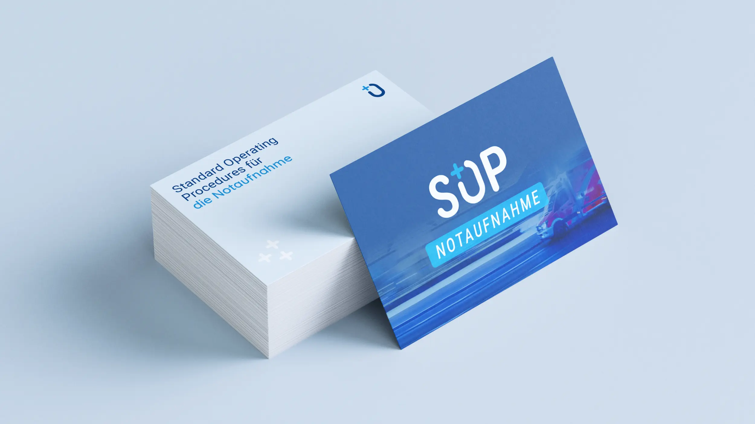 Stapel Visitenkarten und Einzelkarte mit SOP-Logo und Rettungswagen-Hintergrund.