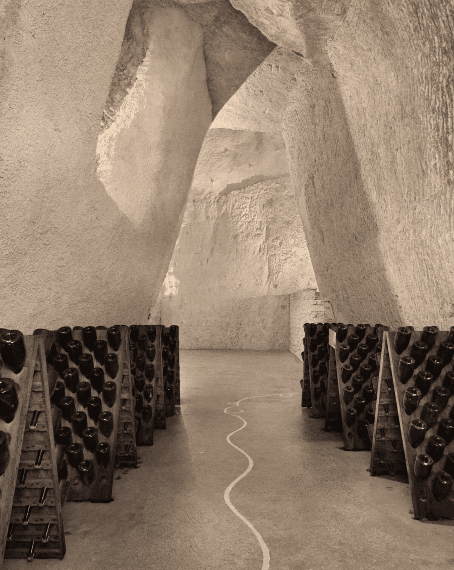 Ancient champagne cellar carved in stone, with bottles aging in riddling racks.