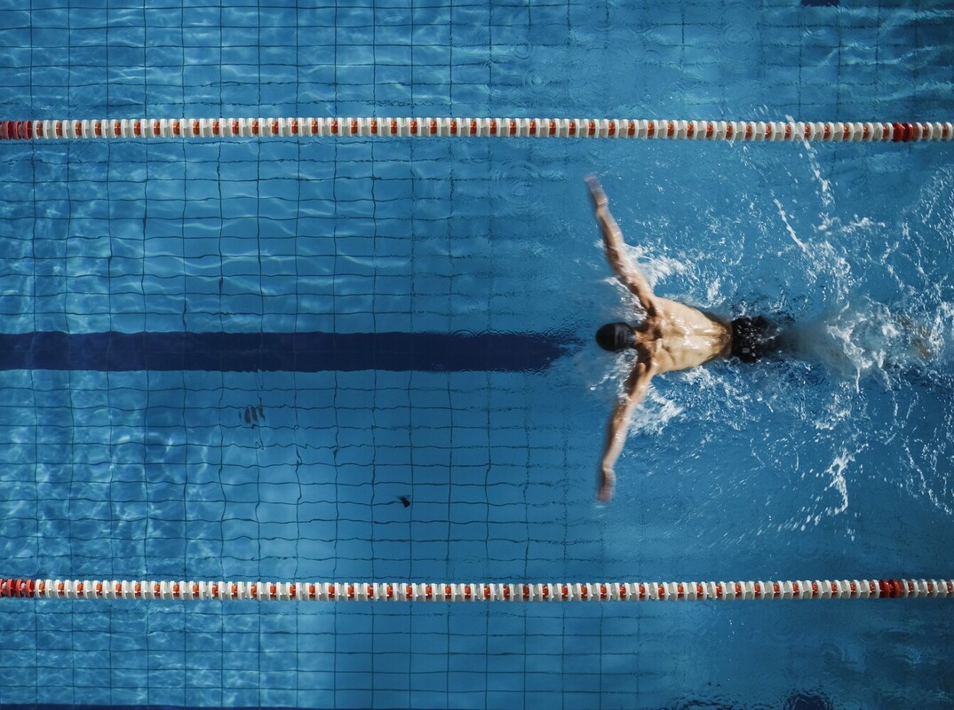 man doing an intense butterfly stroke interval as part of his swimming workouts to lose weight