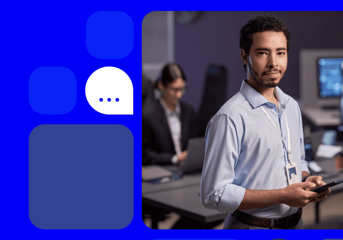 An insurance worker stands against an office backdrop holding a digital device
