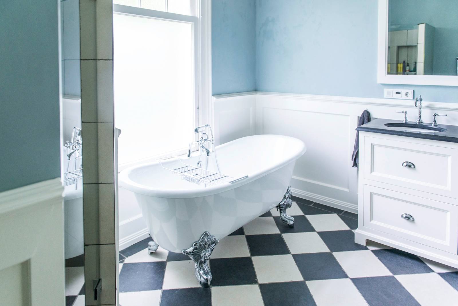 badkamer klassiek met bad op pootjes, zwart-witte tegels en blauwe muren