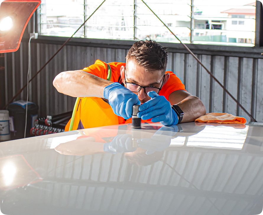 Detailer polishes car surface with buffing tool.