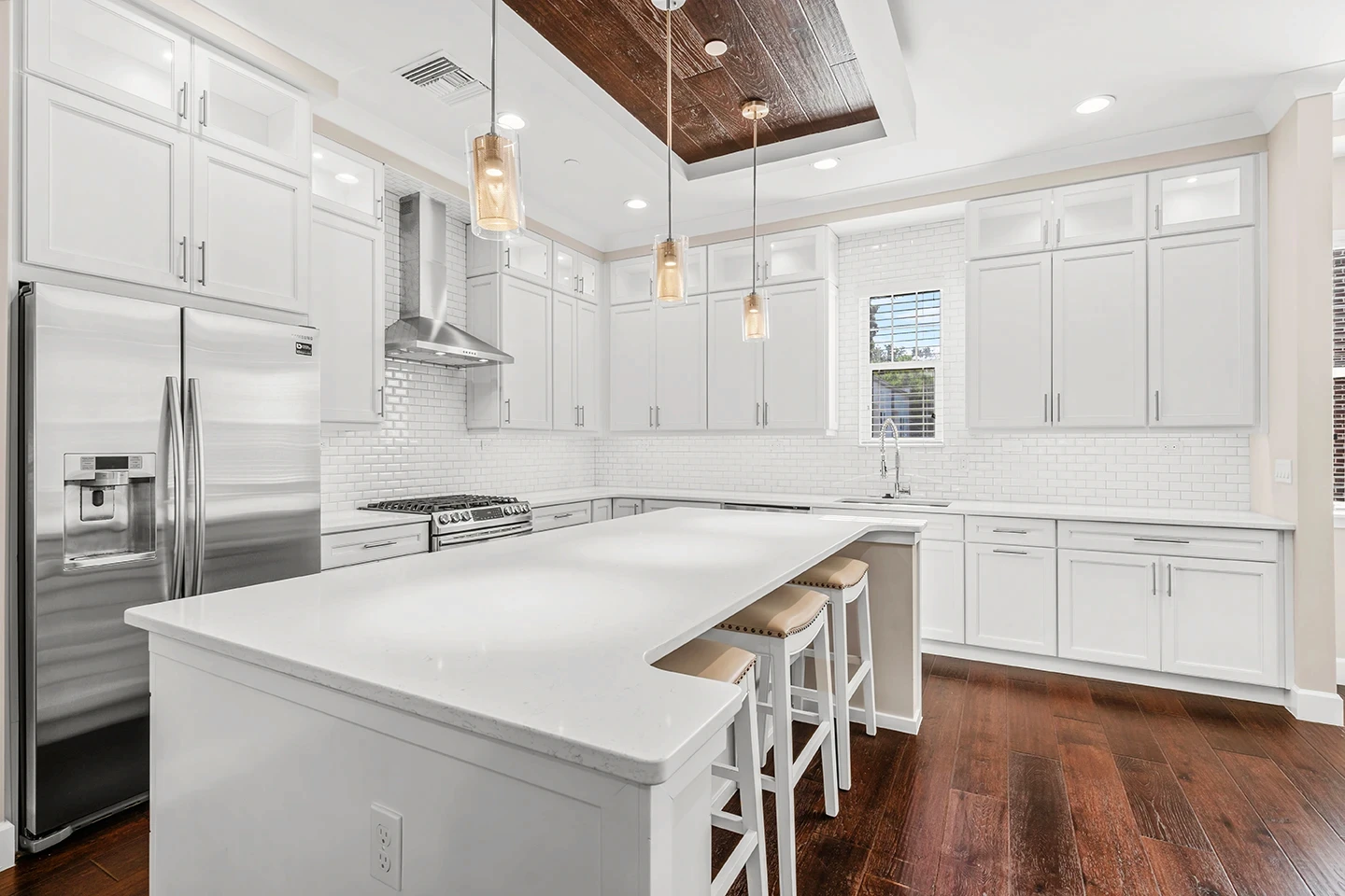 Bright Winter Garden townhome kitchen with white cabinetry, subway tile backsplash, quartz island with seating and wood flooring