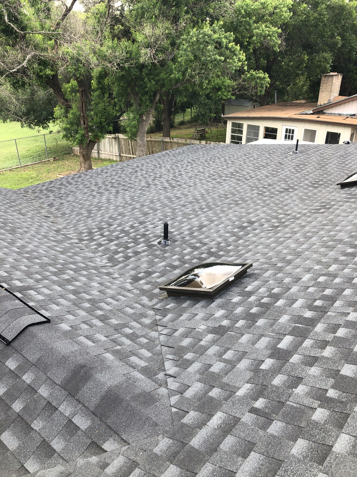 Close view of a dark architectural shingle roof with a roof vent and raised ridge line; manufacturer not verified.