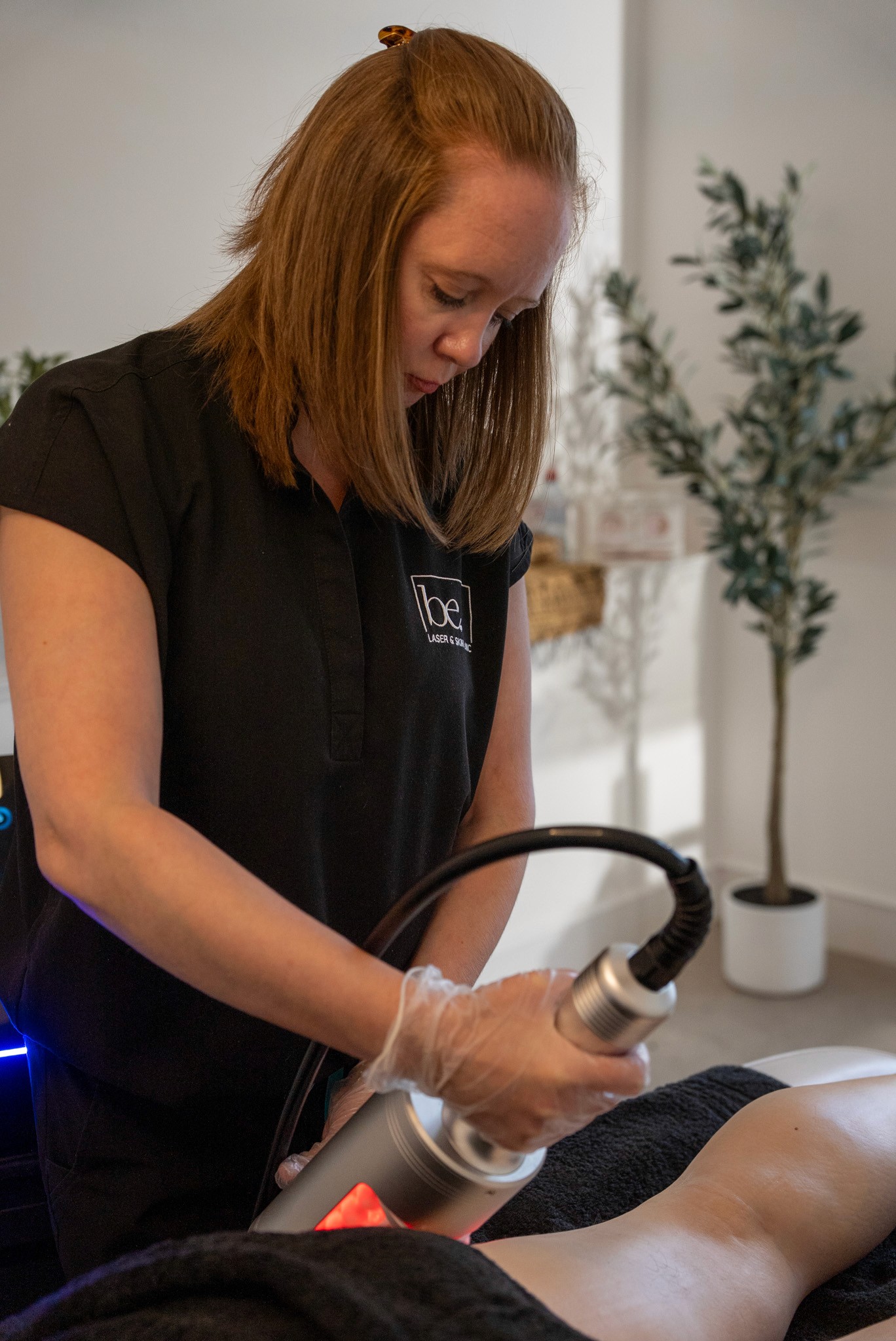 Technician using laser treatment on client's leg