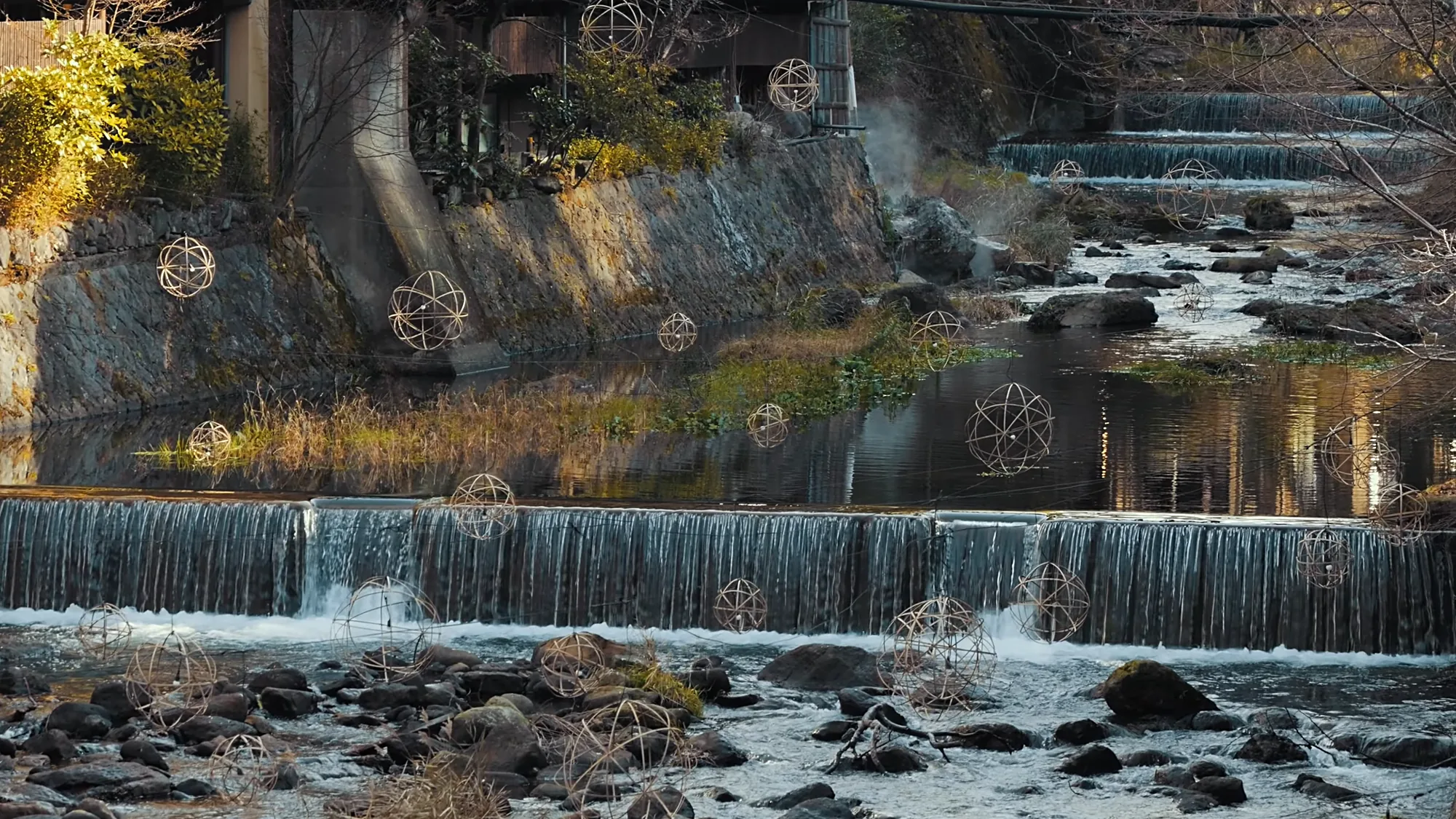 Bamboo lantern spheres above the river weir at Kurokawa Onsen in autumn