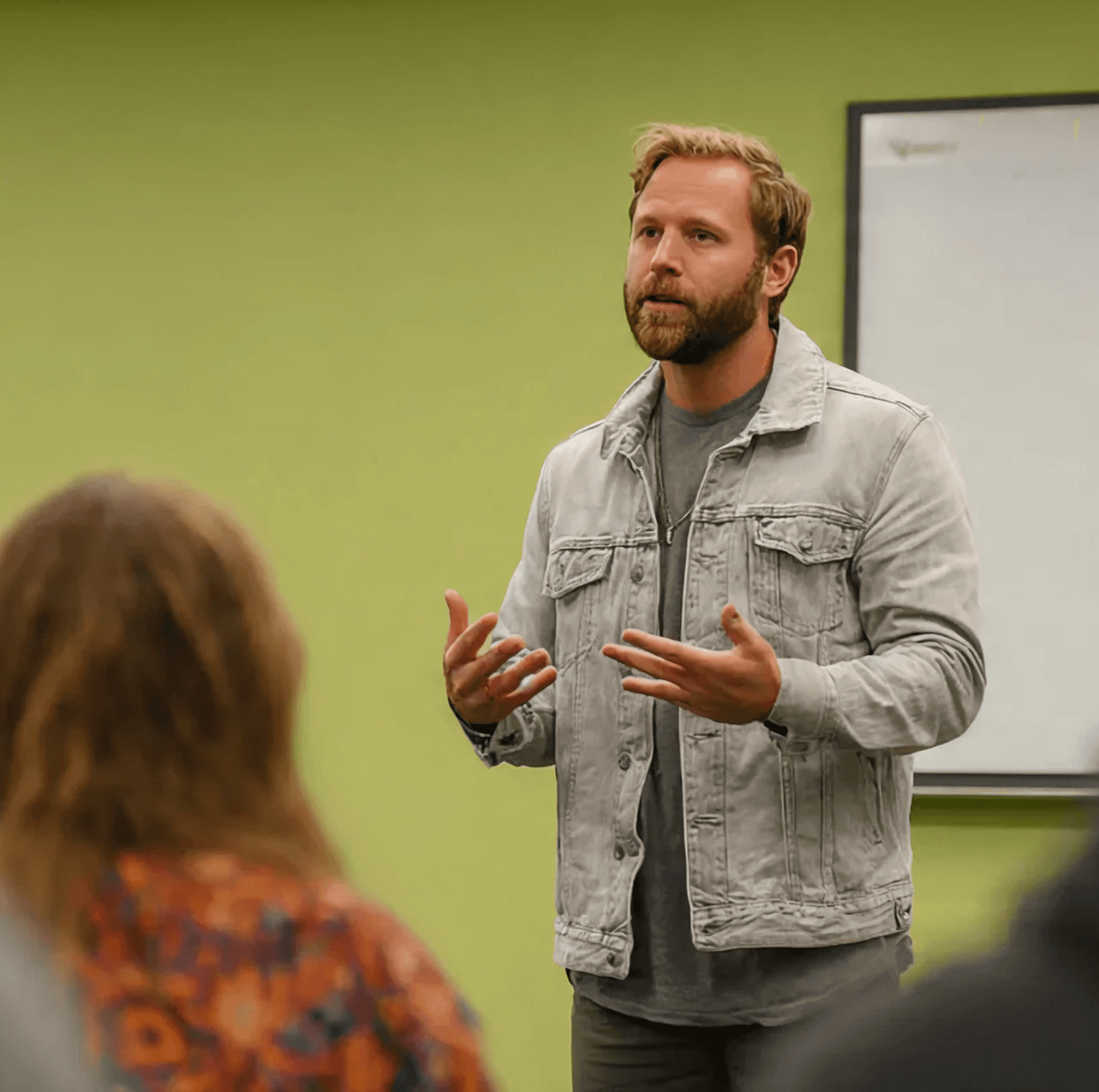 Young man in green sweater asks a question into a conference mic.