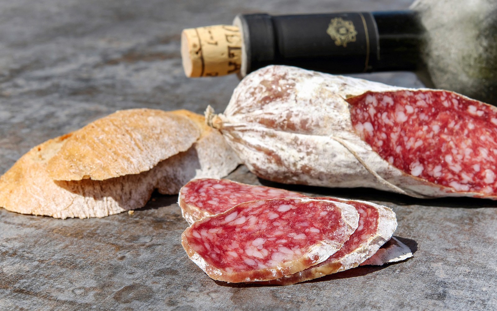 Sliced salami, bread, and wine bottle on a table in Chianti.