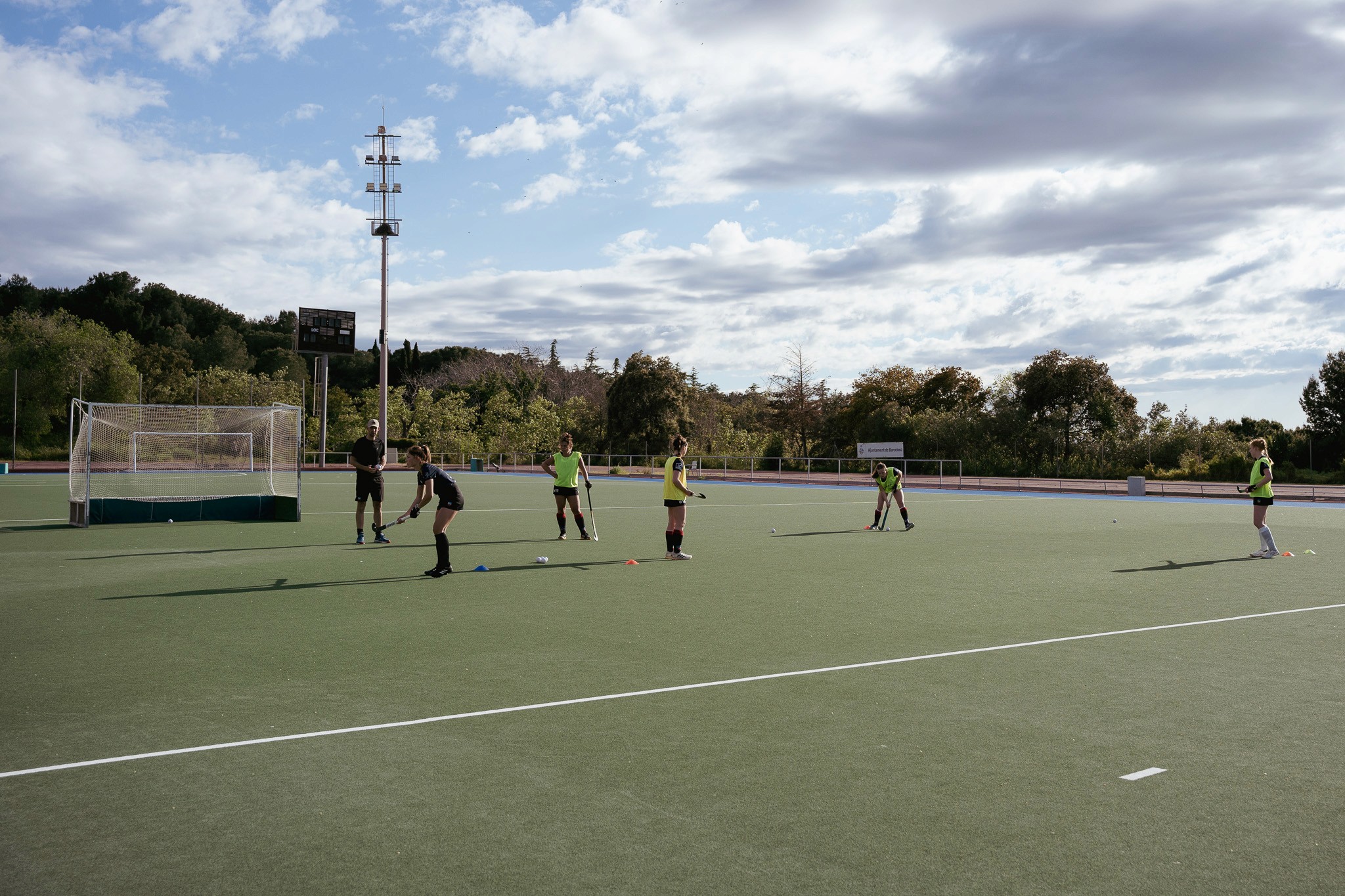 Uitzicht op het hockeyveld van Catalònia Hoquei Club op Montjuïc, omringd door groene bomen en de skyline van Barcelona.