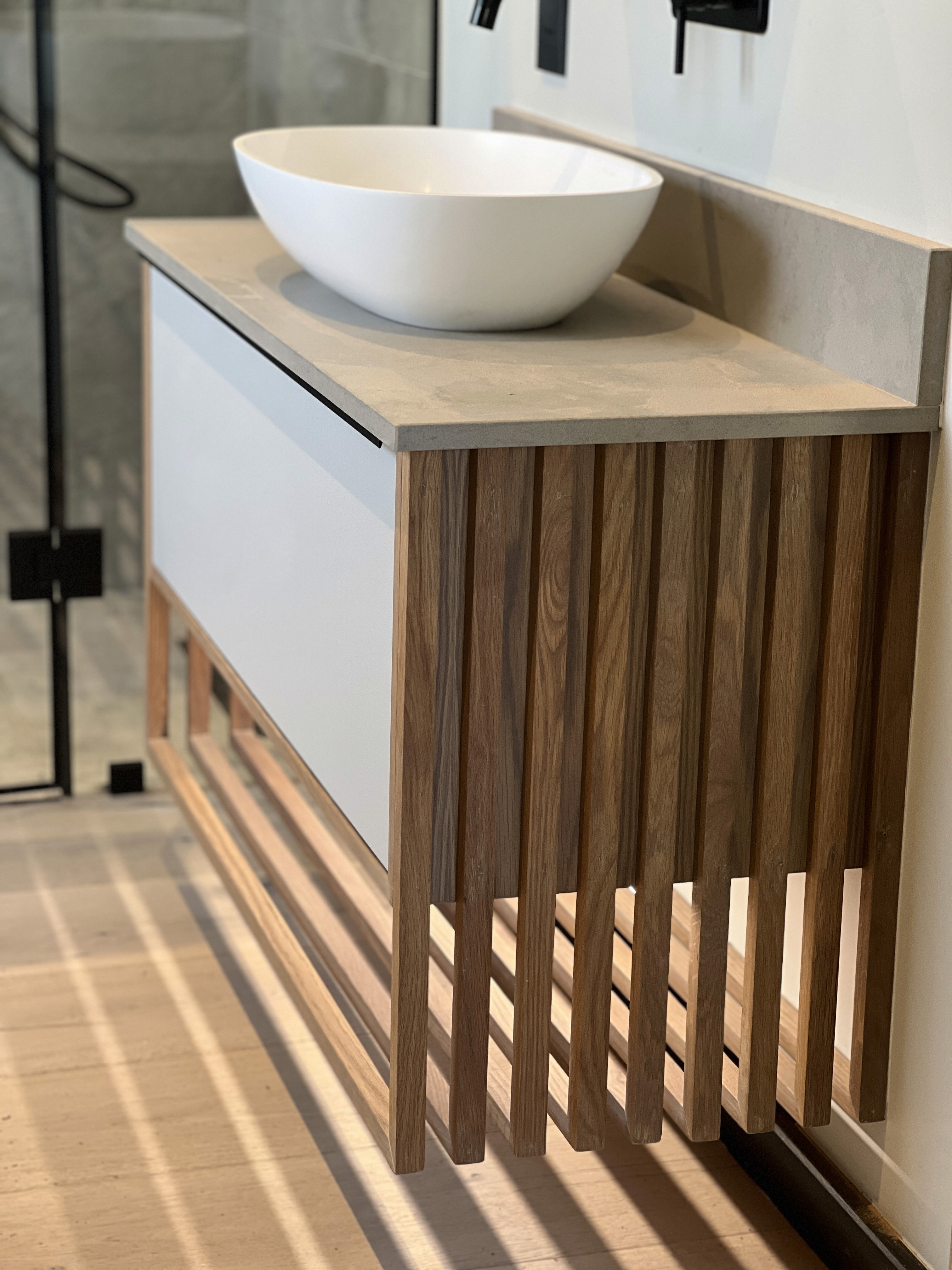 Minimalist living space featuring oak flooring, timber wall panels and panoramic windows with natural light.