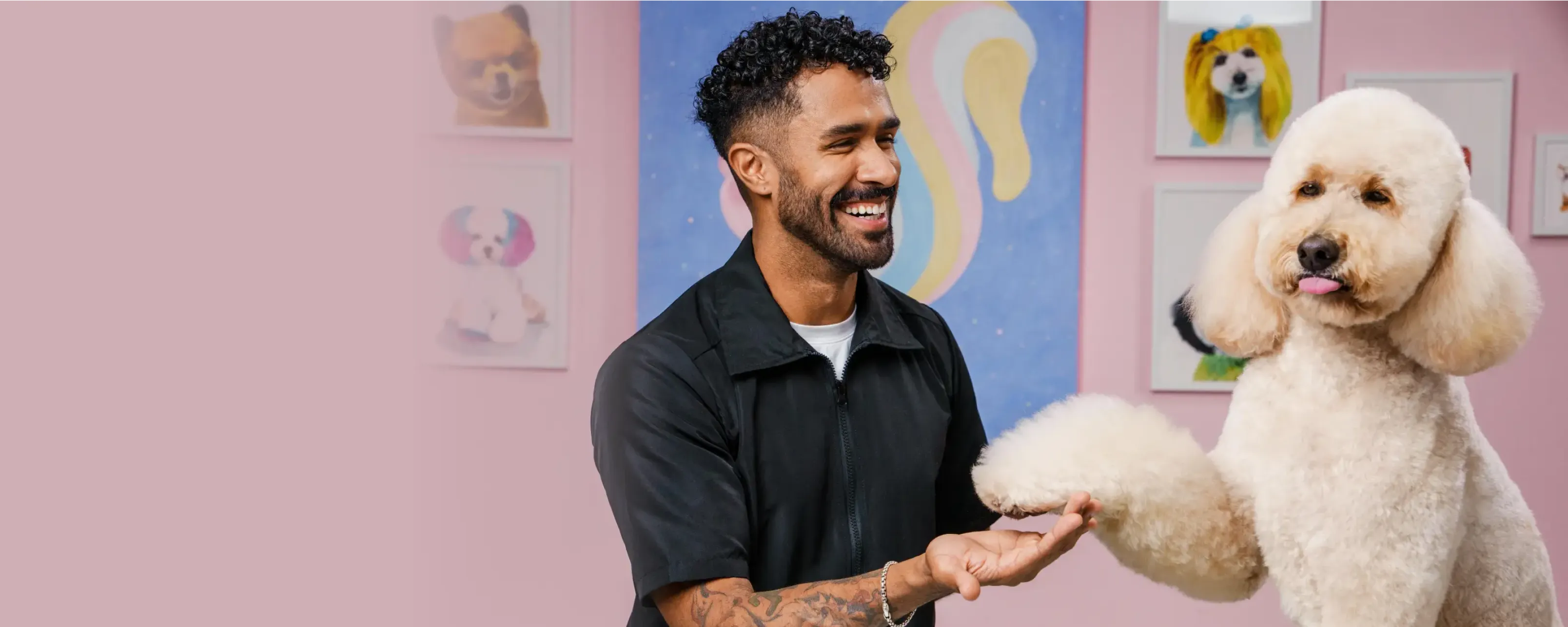 Smiling groomer shaking paws with a cream-colored dog at MIMO La Jolla.
