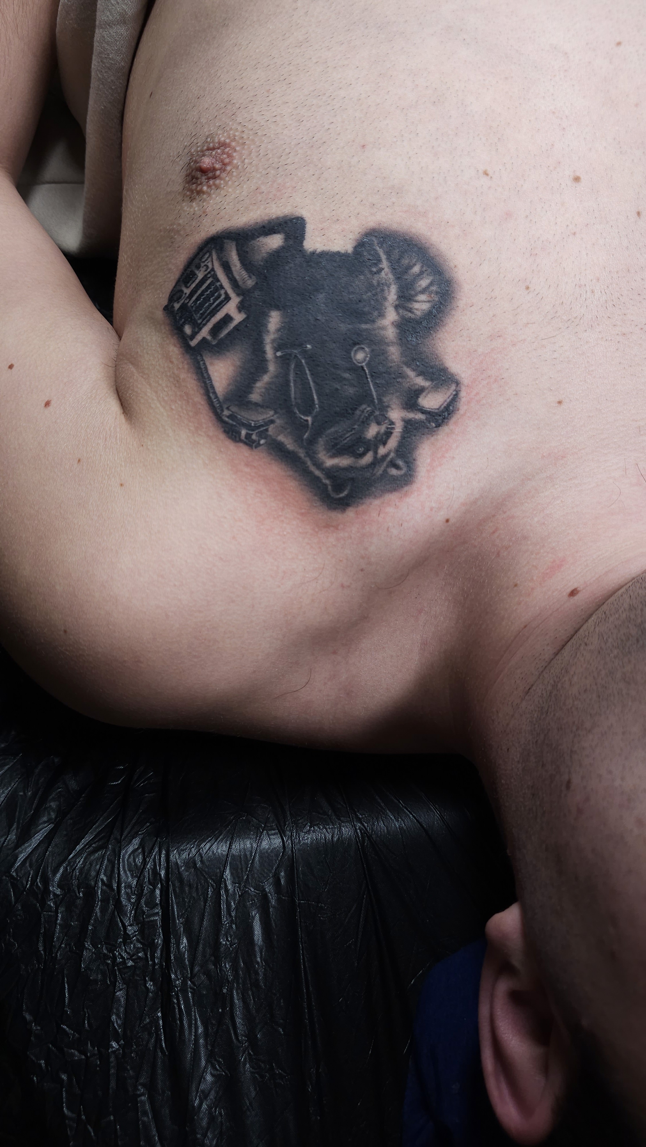 Realismus Tattoo auf der oberen Brust: ein kleiner Waschbär mit Stethoskop und defibrilator in der Hand.