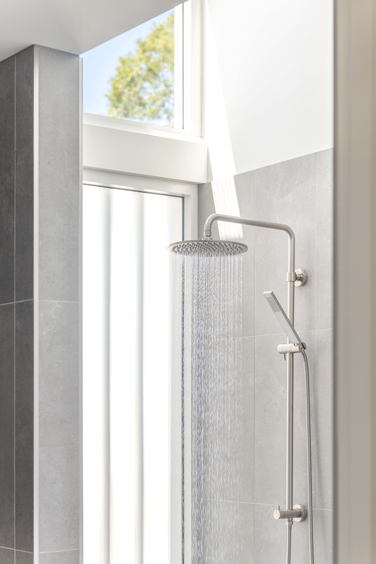 Shower detail at The Stables with skylight illumination, minimal fixtures, and a calm, light-filled bathroom setting.