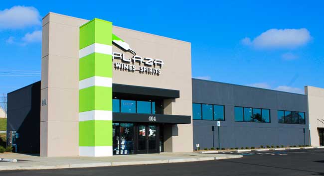 Modern building with green accents, large windows, and clear blue sky background.