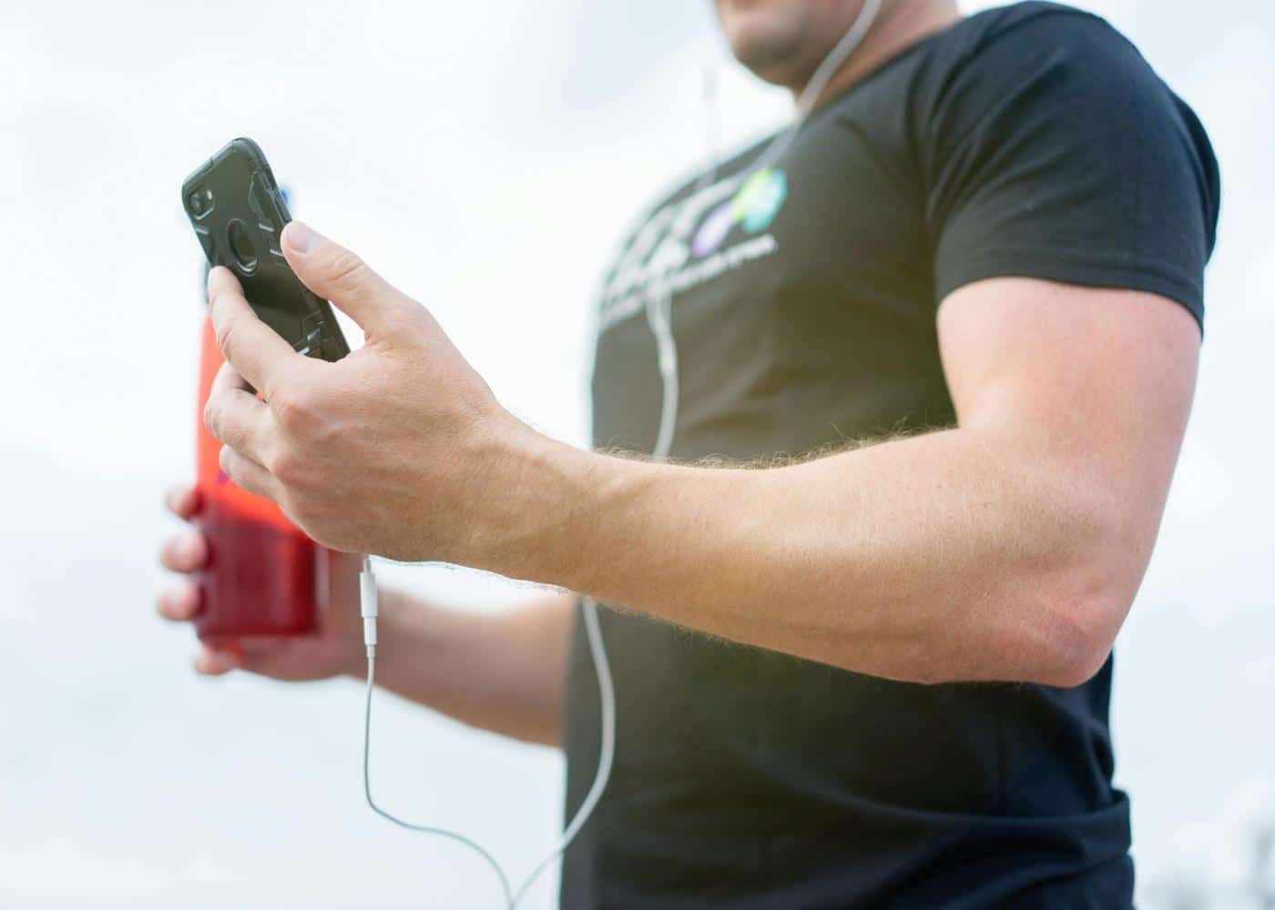 Man holding drink in one hand and looking at smartphone in other hand