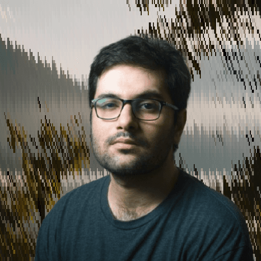 Professional headshot of a man wearing glasses against a natural background.