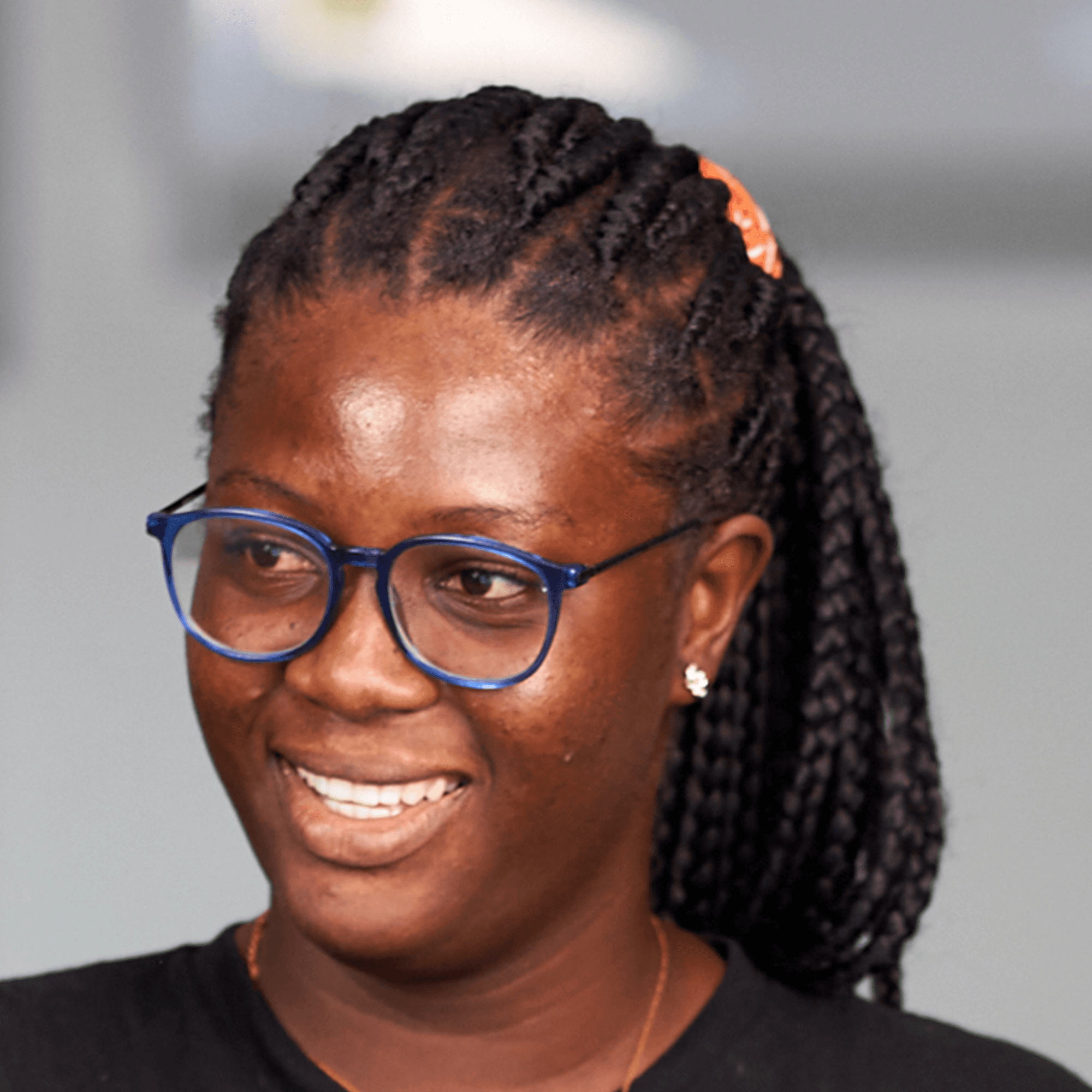 Young woman with glasses and braids, smiling slightly.