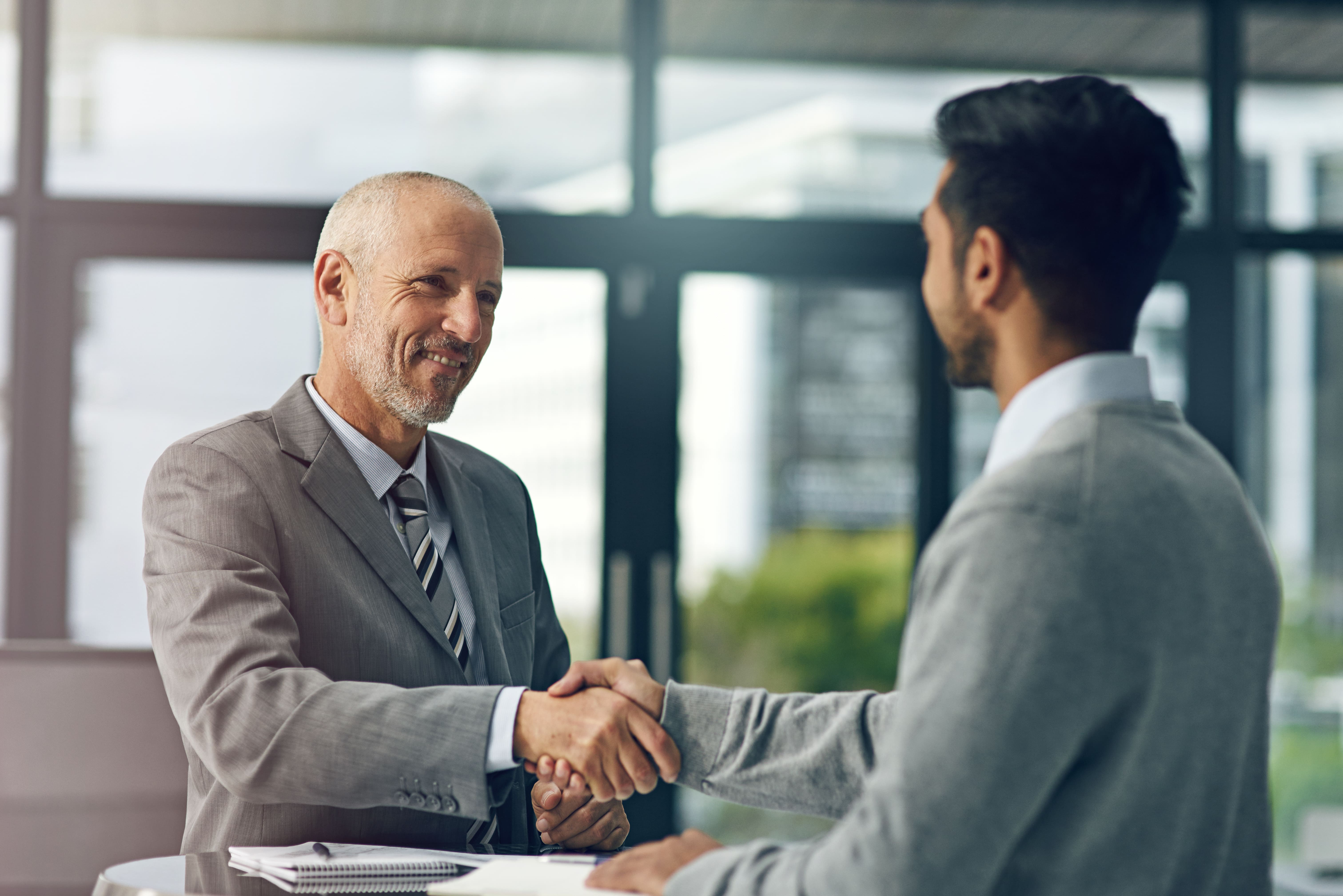 wo businessmen shaking hands in a professional setting.