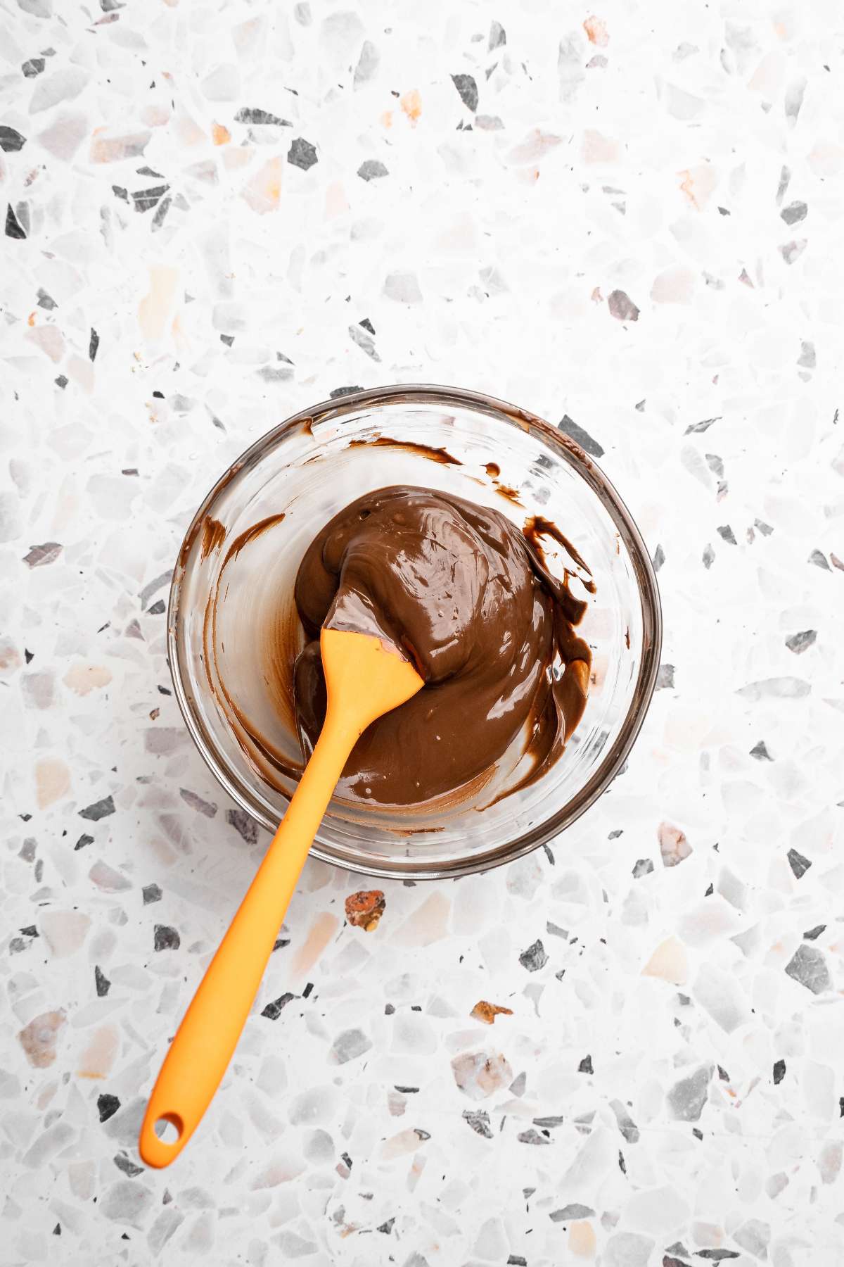 Stirring melted chocolate in a small bowl.