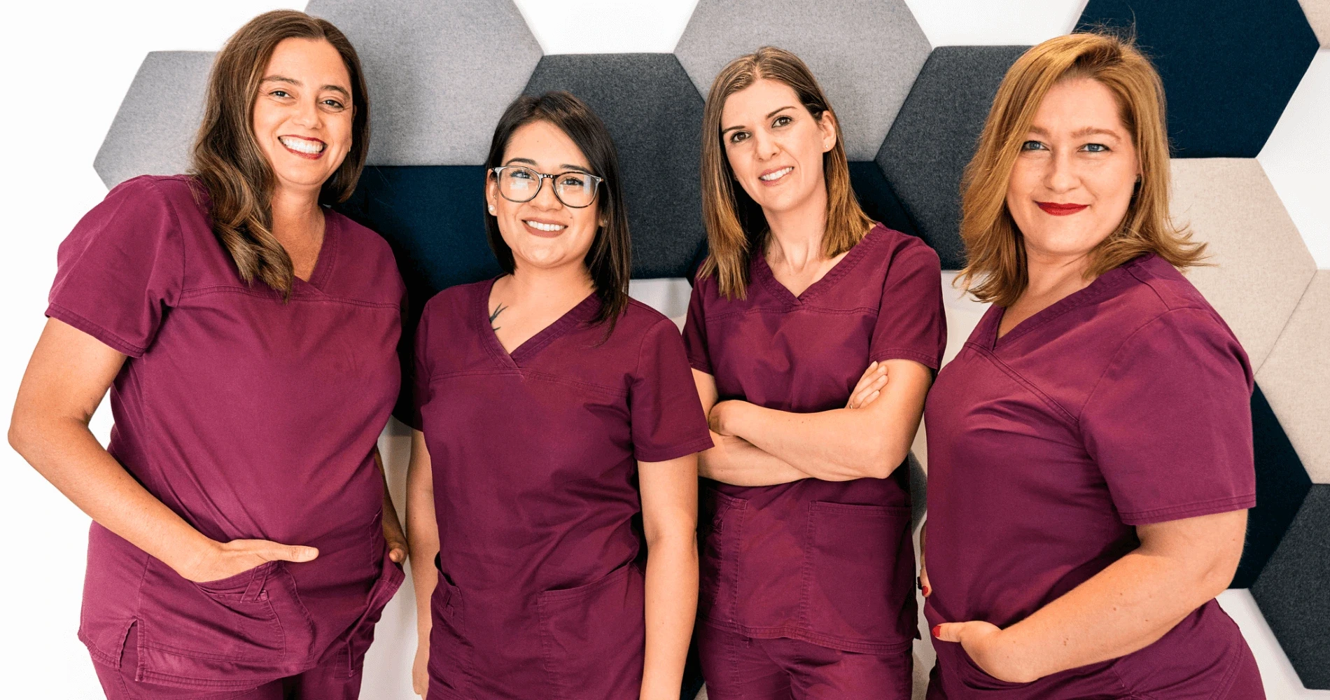 Group of four female clinical staff wearing maroon scrubs smiling together — recruitment banner reading “Join Us at Venus Women’s Clinic”.