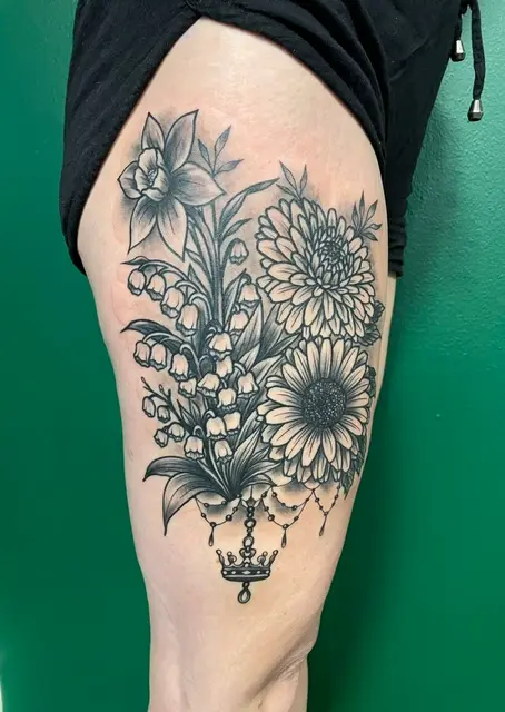 Svartvit blomstertatuering med krona på lår, gjord av High Heels Tattoo i Västervik