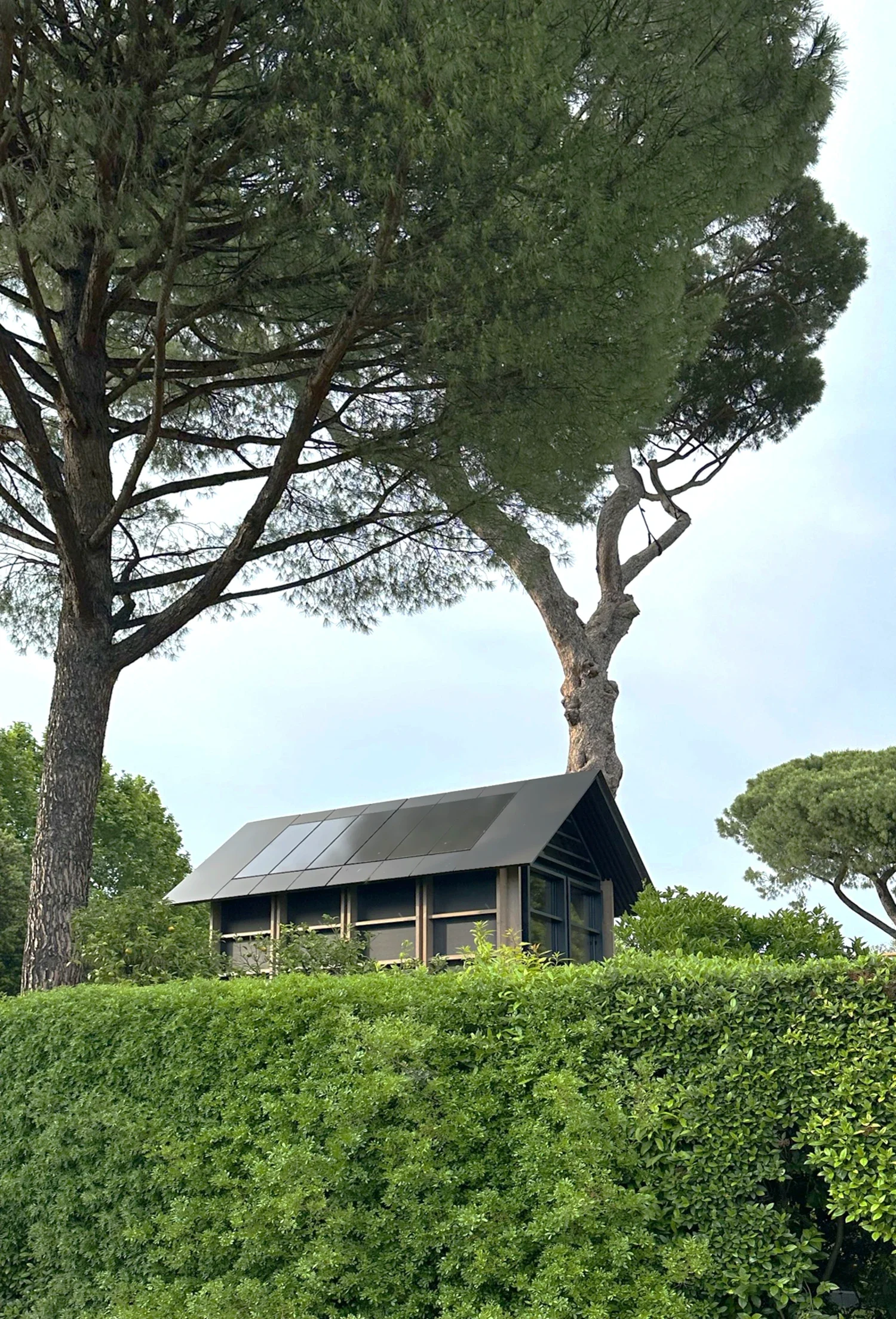 Écolodge Villa Médicis avec panneaux solaires sur le toit, vue depuis les haies du jardin 