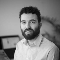 Profile portrait of a man in a white shirt against a light background