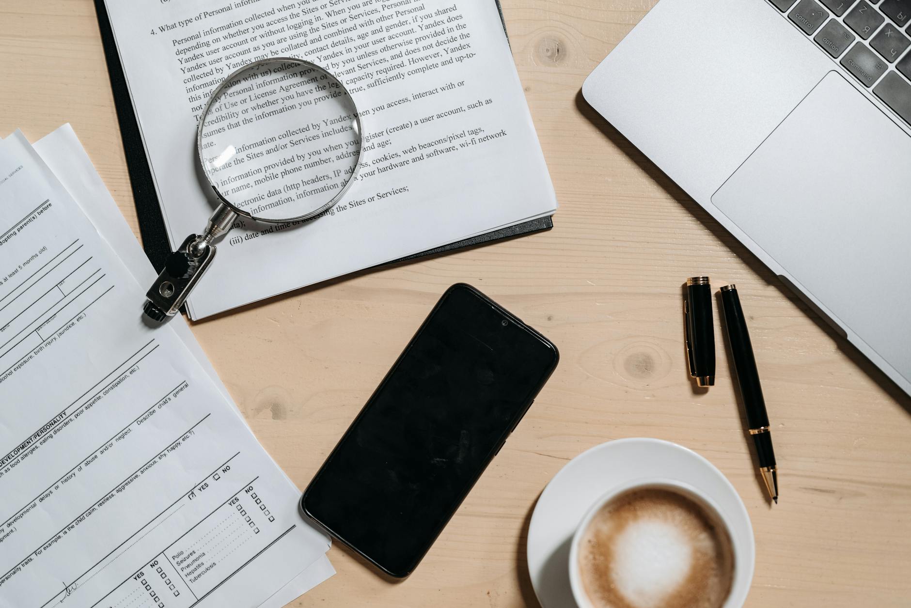 Documente fiscale cu lupă, laptop și cafea pe birou organizat