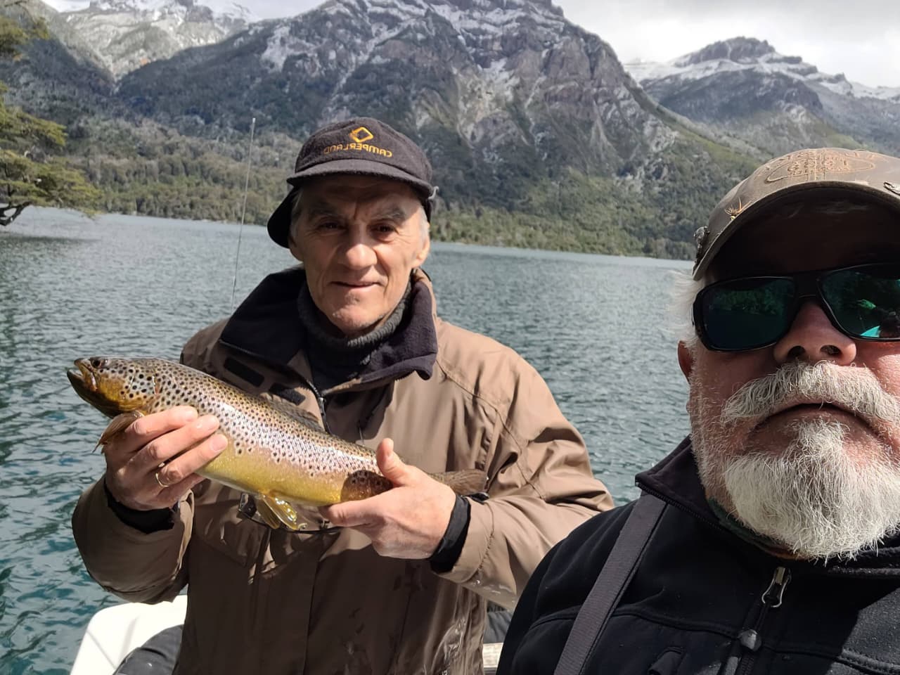Eduardo remando y otro cliente atrás mostrando la trucha que capturó