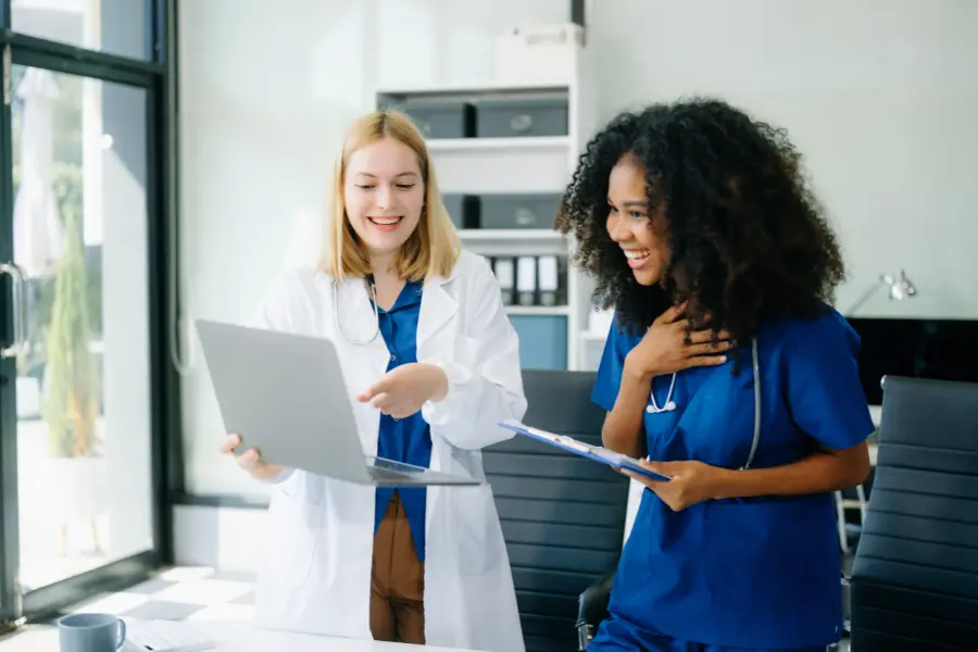 AI tools for CPT coding demonstrated by medical professionals reviewing data on laptop in clinical setting.