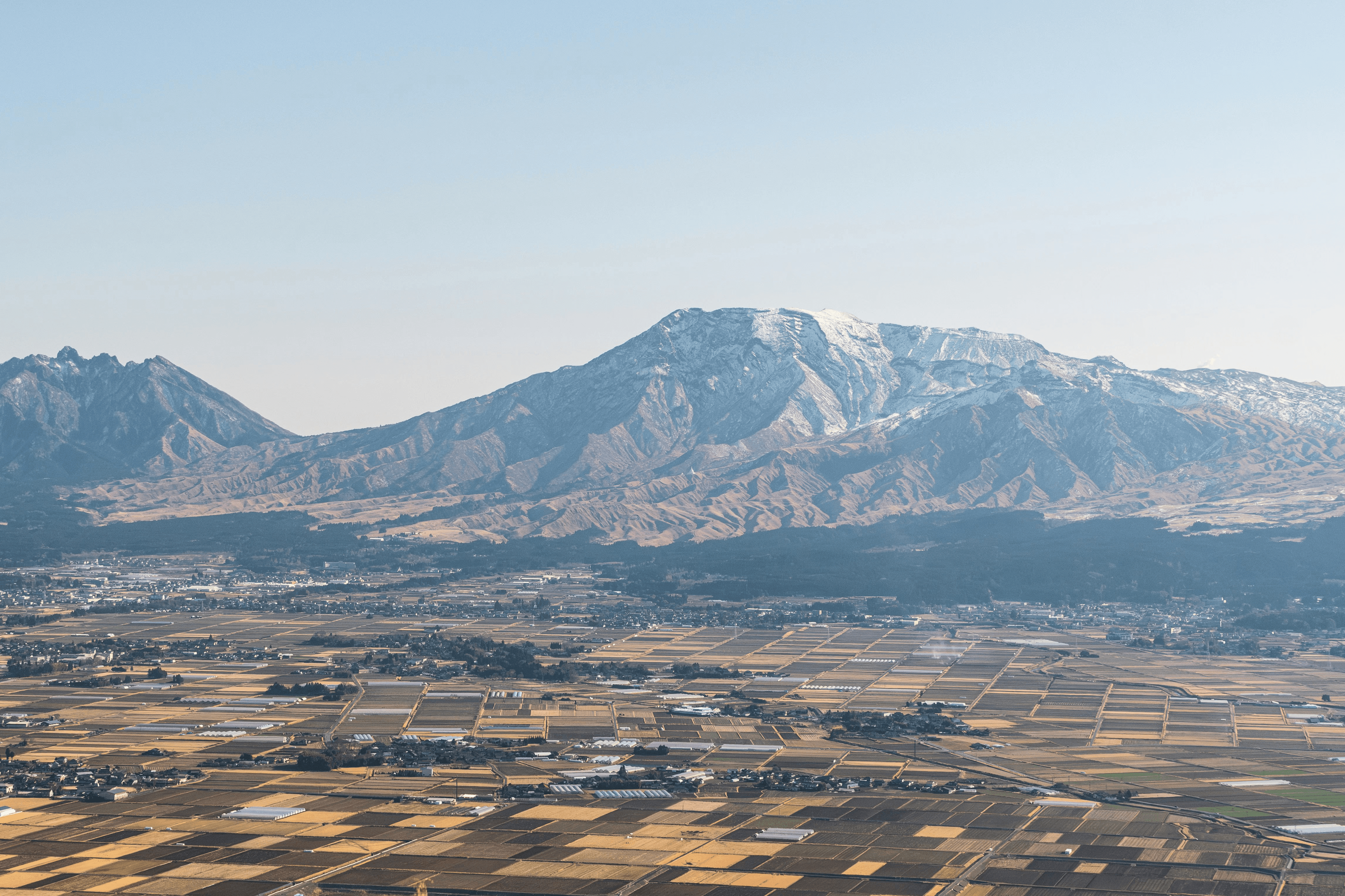 Snow-capped mountains rise above a distant town.