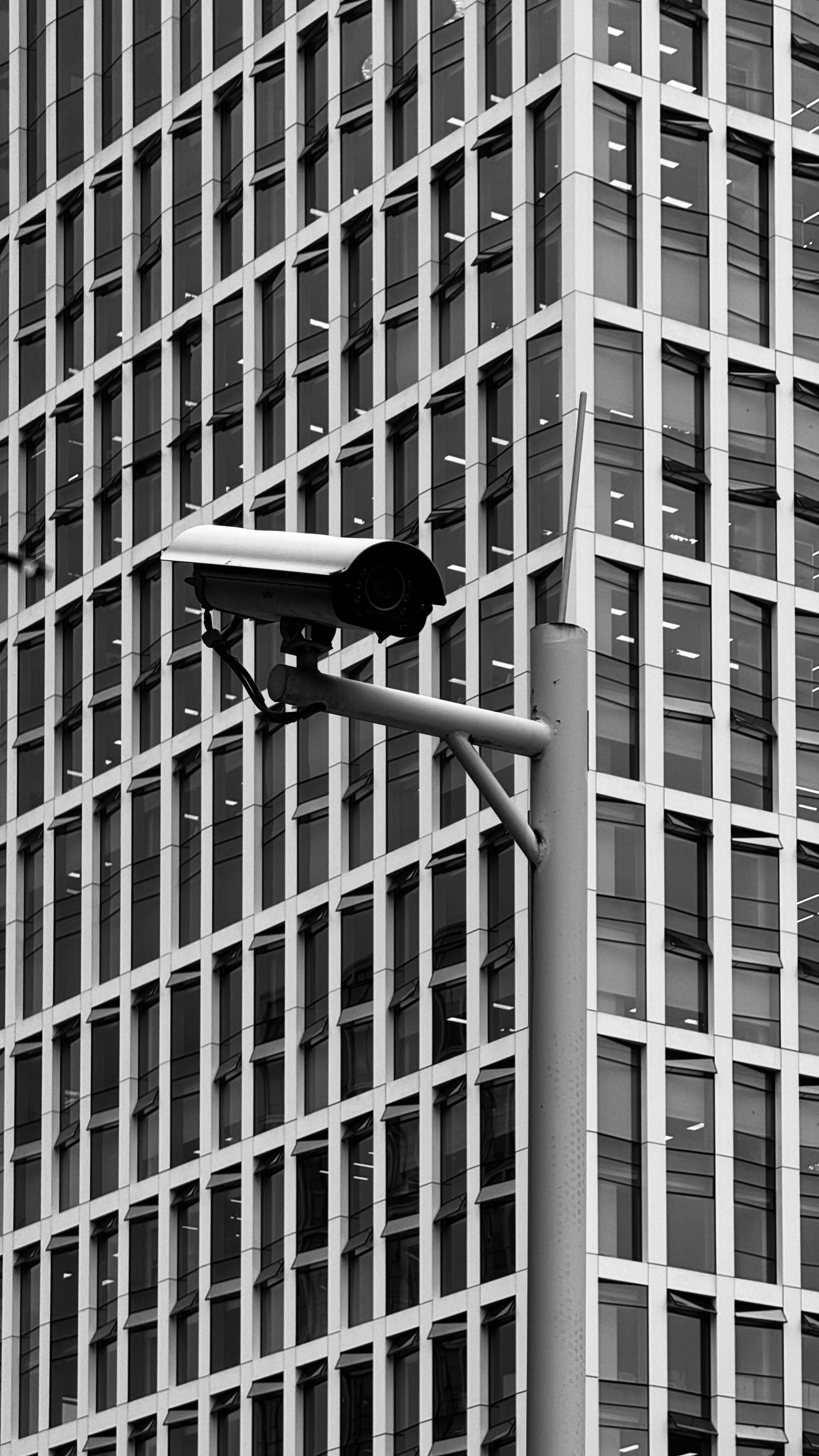 A black and white photo of a street light in front of a tall building