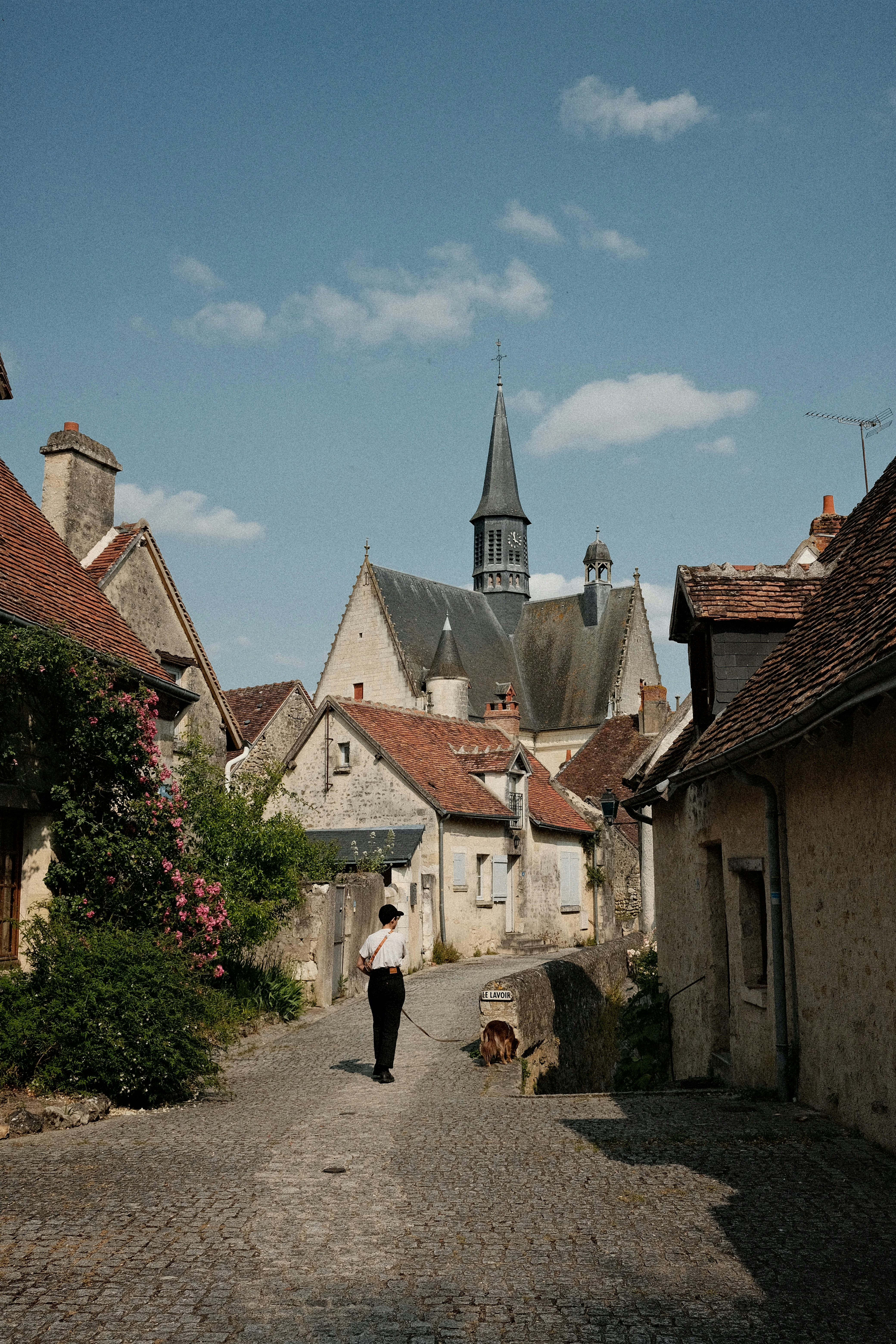 A person walks down a cobblestone street in a village.