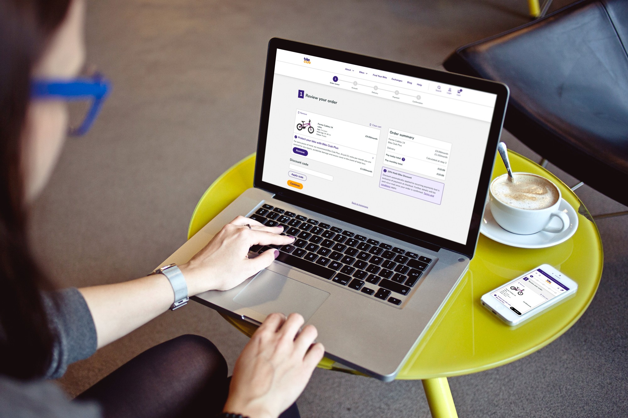 Woman in a relaxed environment with the BikeClub checkout page open on her laptop and phone in front of her.