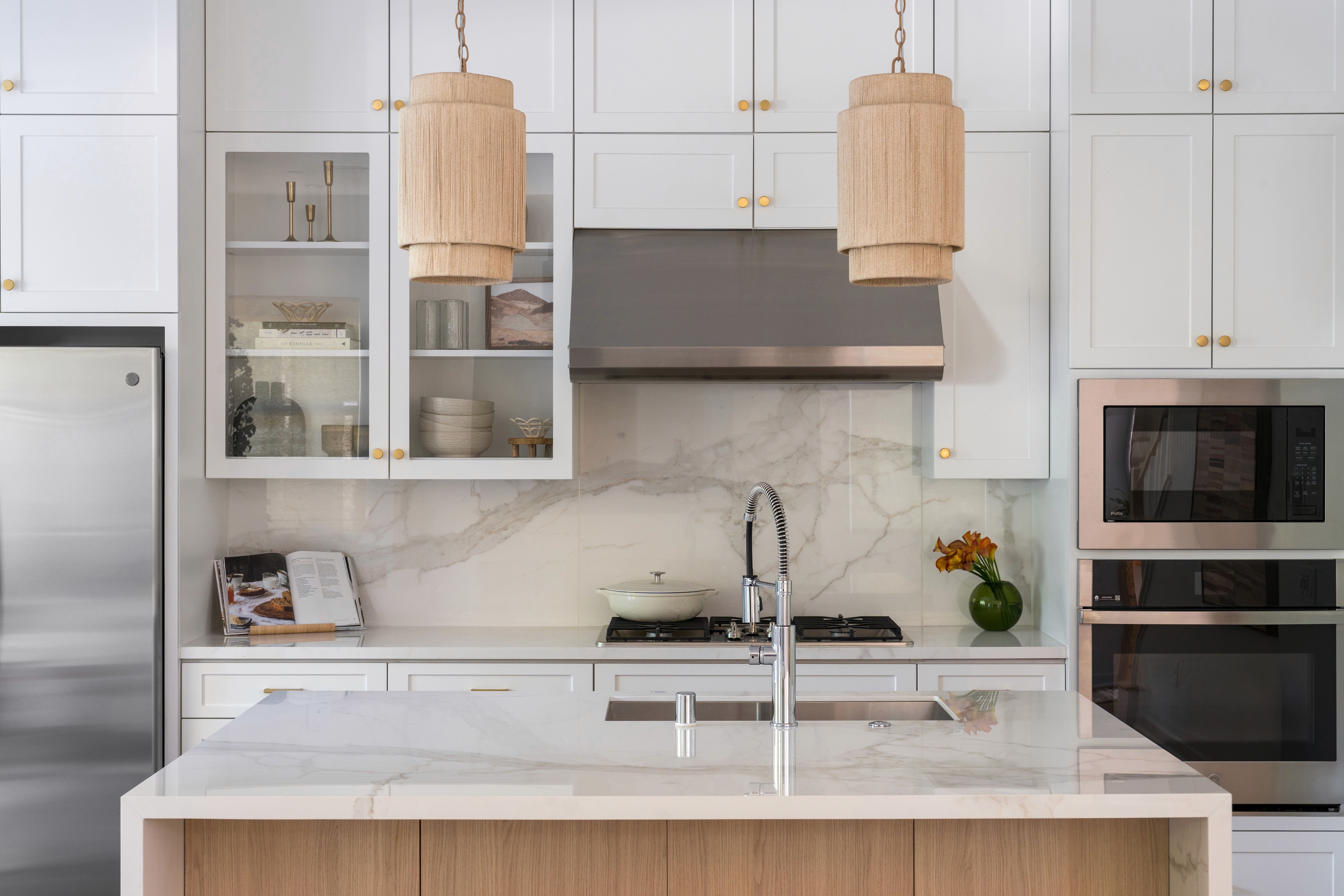 White kitchen with rattan  pendant lighting and marble counter tops by Jubilee Interiors in Arcadia, California