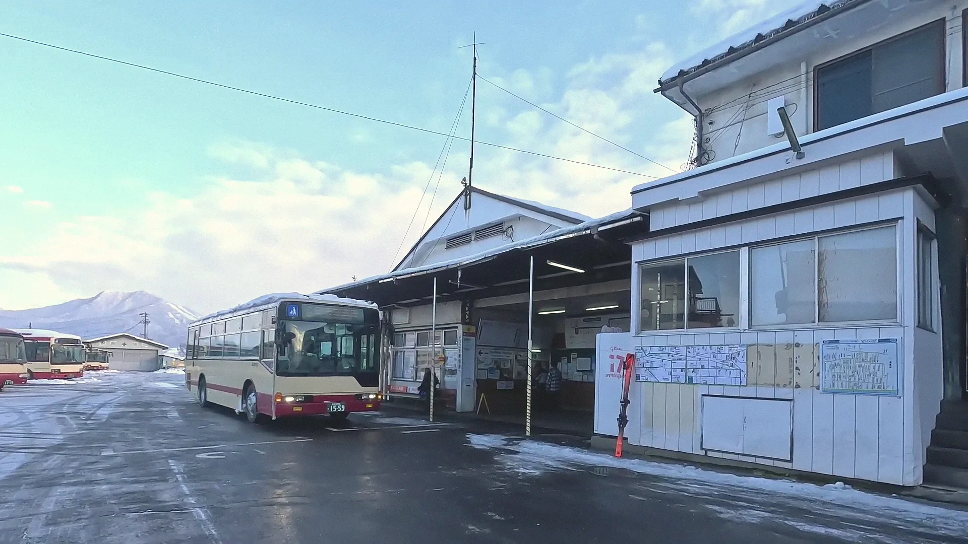Yudanaka station entrance with a waiting bus and mountains behind